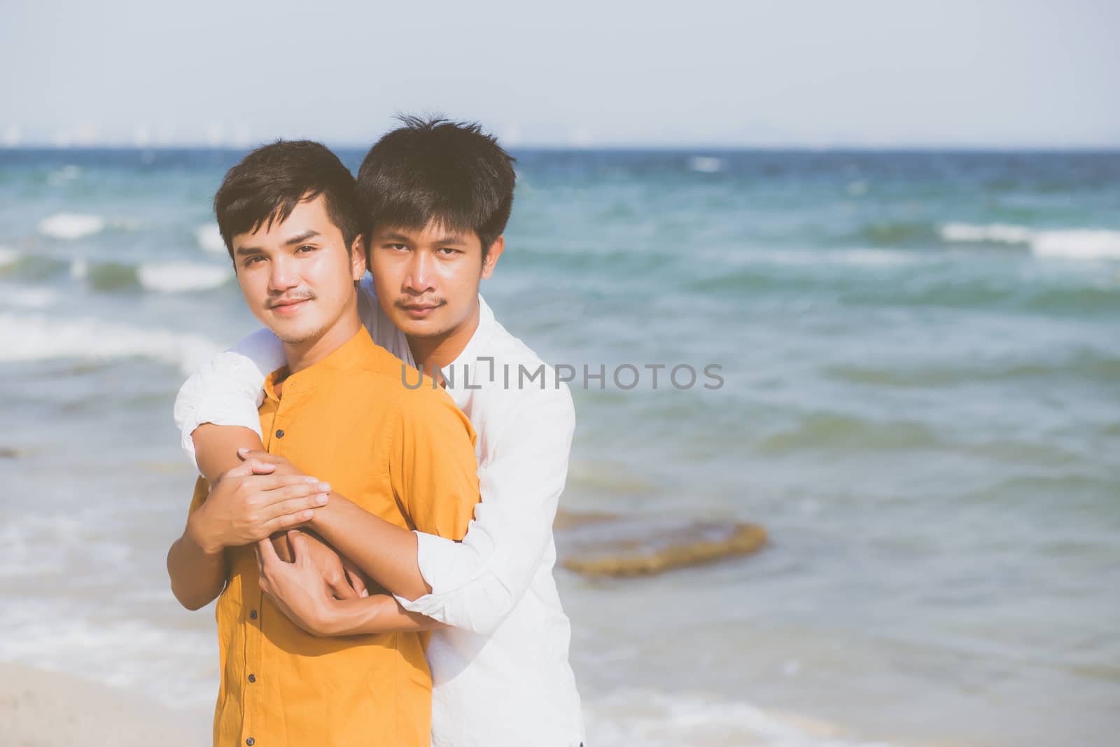 Homosexual portrait young asian couple standing hug together on beach in summer, asia gay going tourism for leisure and relax with romantic and happiness in vacation at sea, LGBT concept.