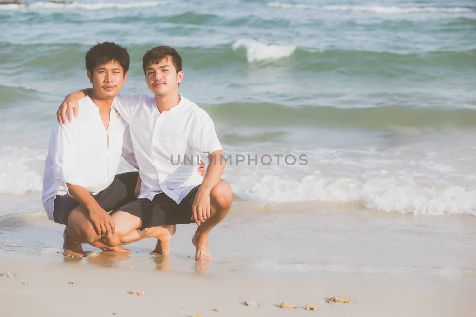 Homosexual portrait young asian couple sitting hug together on beach in summer, asia gay going tourism for leisure and relax with romantic and happiness in vacation at sea, LGBT legal concept.