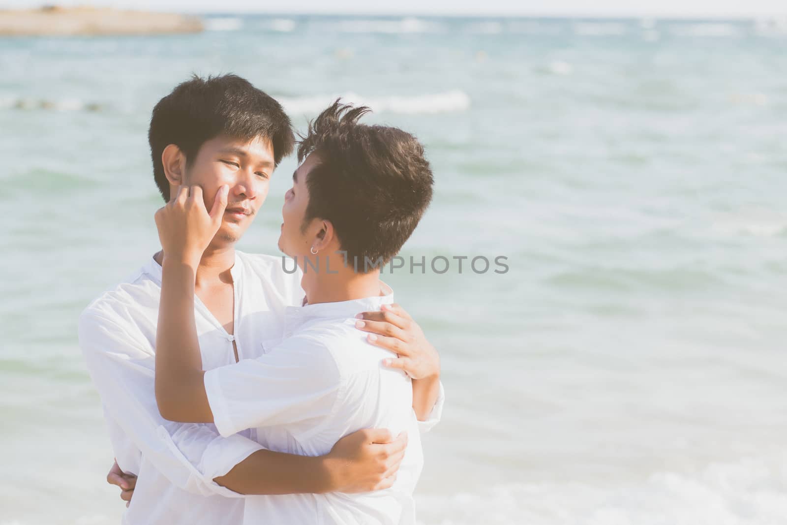 Homosexual portrait young asian couple standing hug together on beach in summer, asia gay going tourism for leisure and relax with romantic and happiness in vacation at sea, LGBT concept.