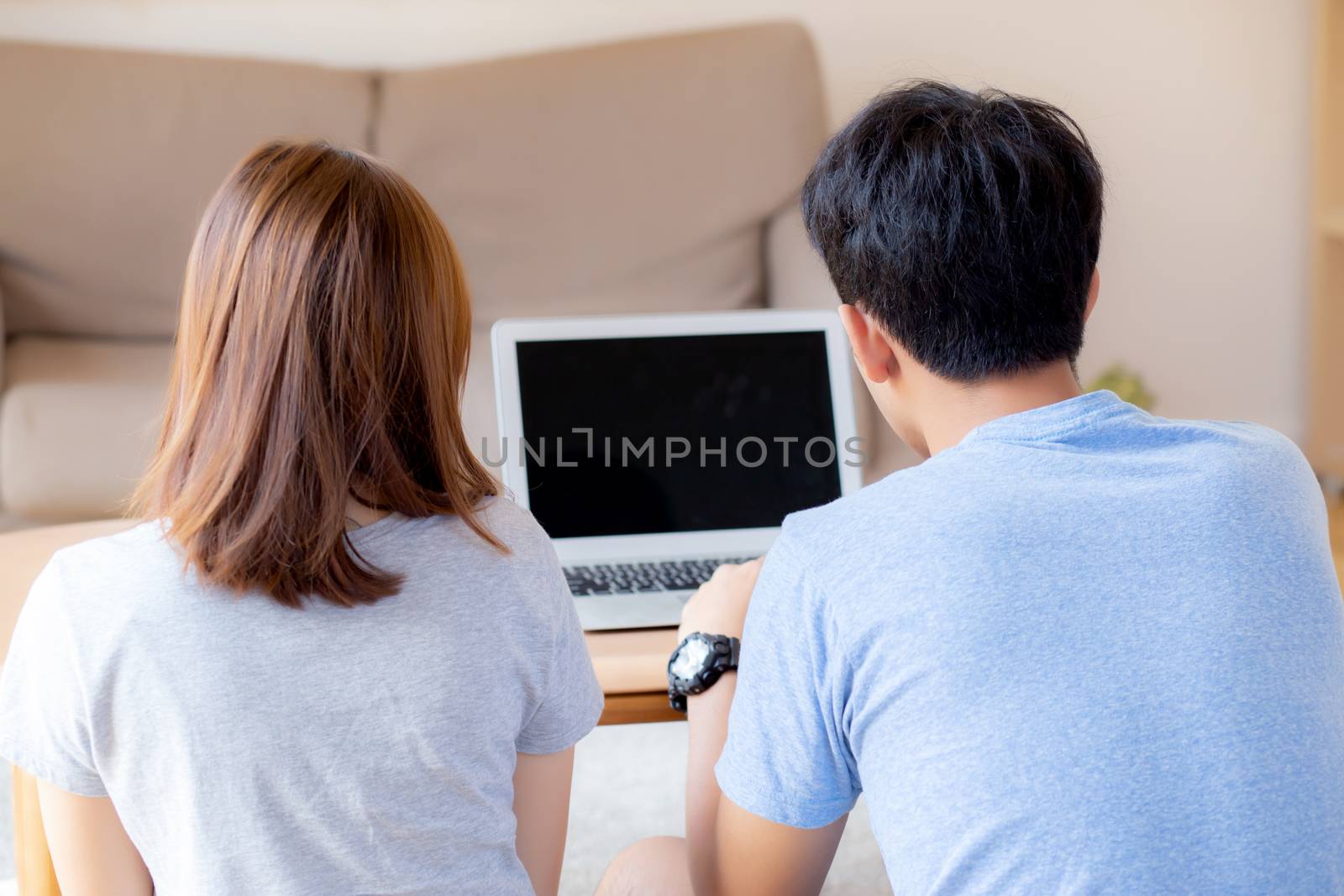 Back view of young asian couple working laptop with blank screen by nnudoo