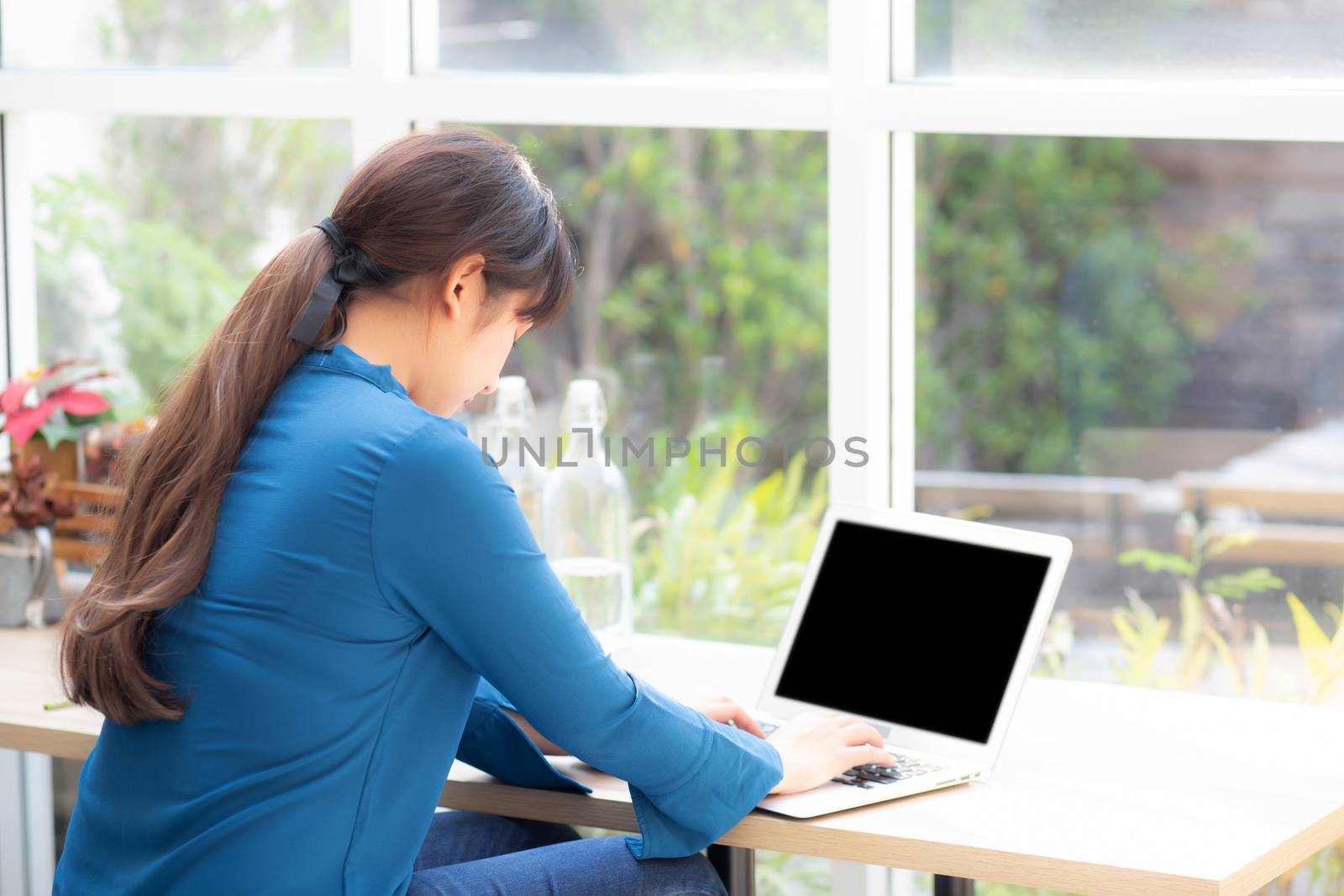 Beautiful portrait asia young woman working online on laptop sitting at cafe shop, professional female freelance using notebook computer, business and communication concept.