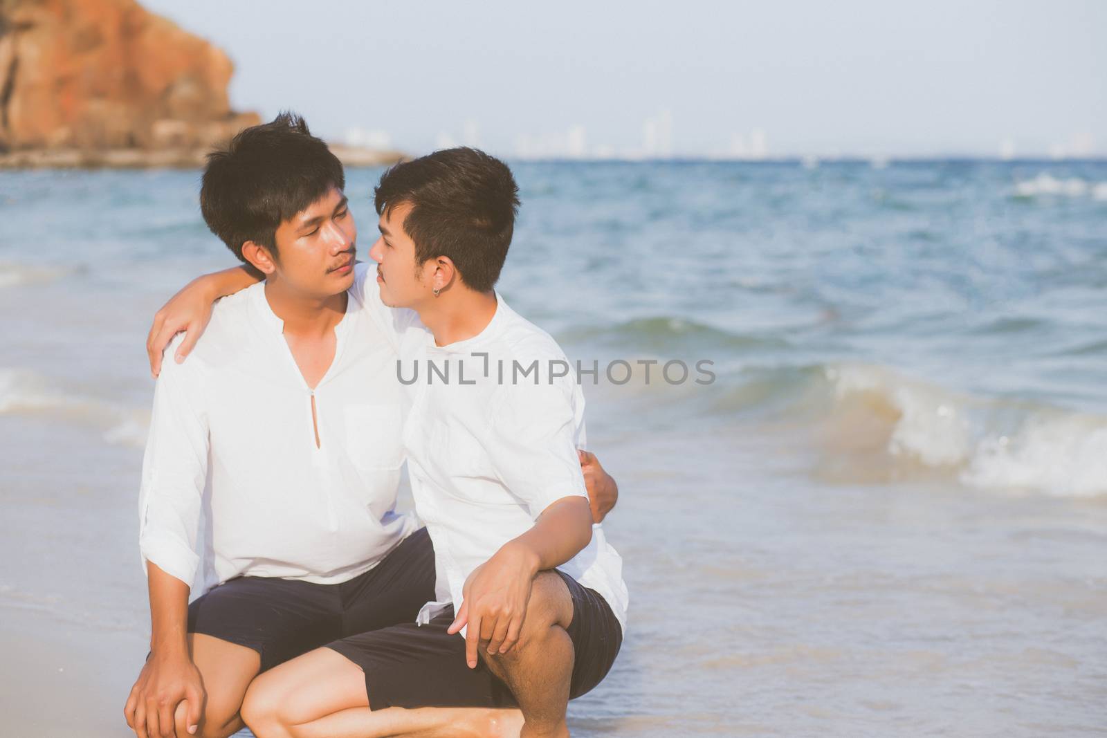 Homosexual portrait young asian couple sitting hug together on b by nnudoo