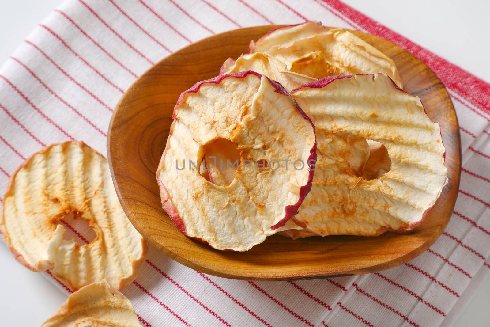 Bowl of dried apple slices - apple chips or rings - on striped tea towel