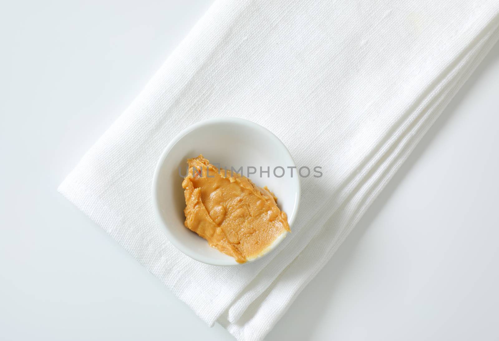 Bowl of crunchy peanut butter on white napkin