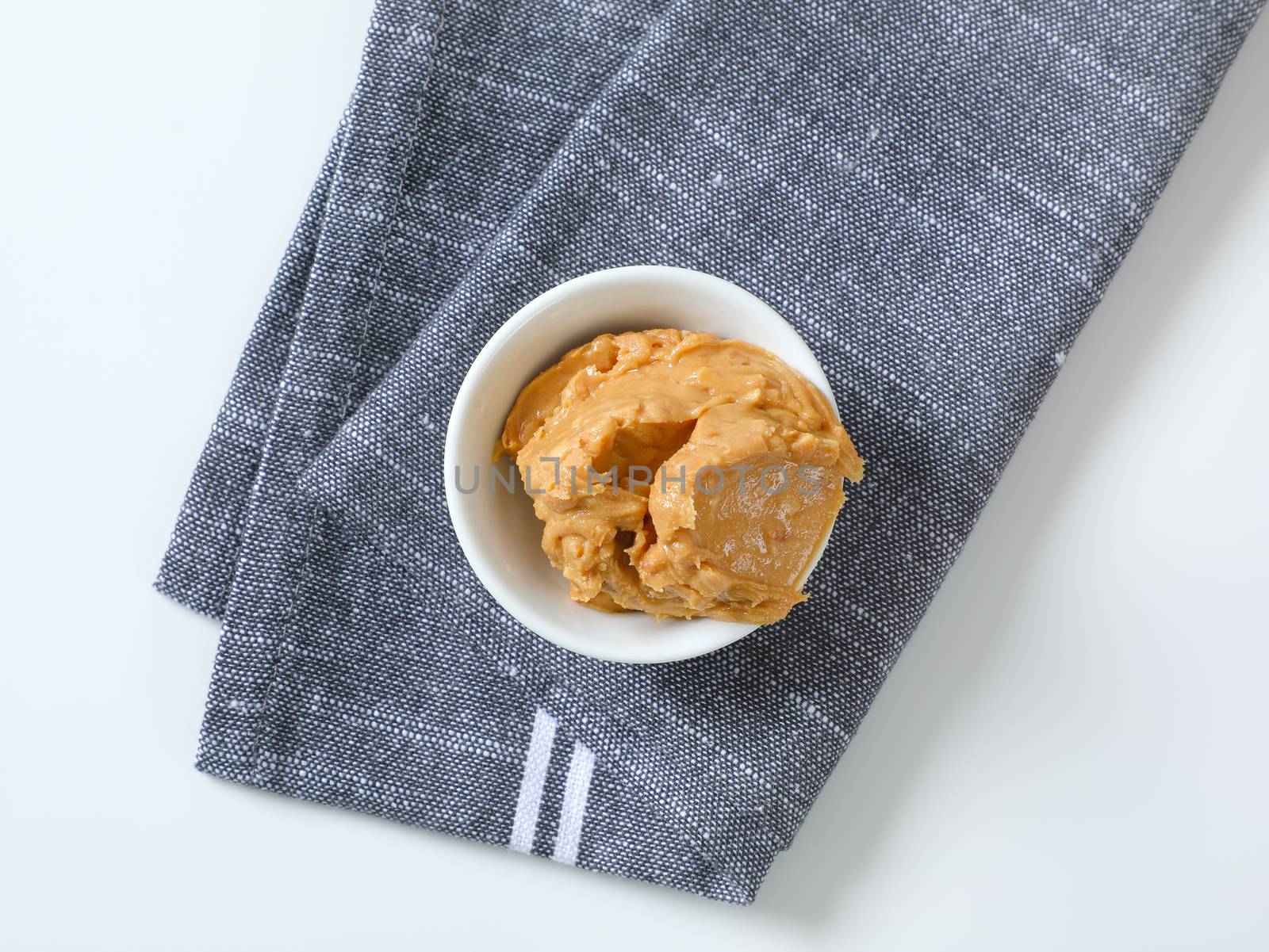 Bowl of crunchy peanut butter on gray napkin