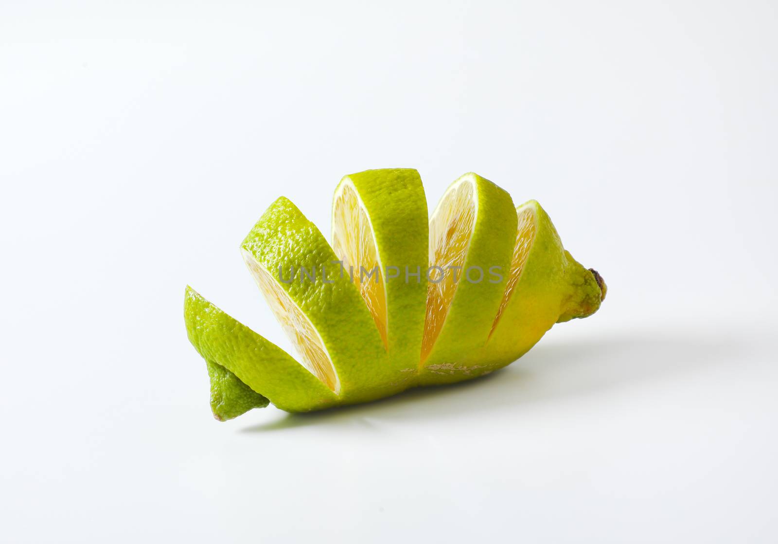 Lemon with green peel and yellow flesh, sliced