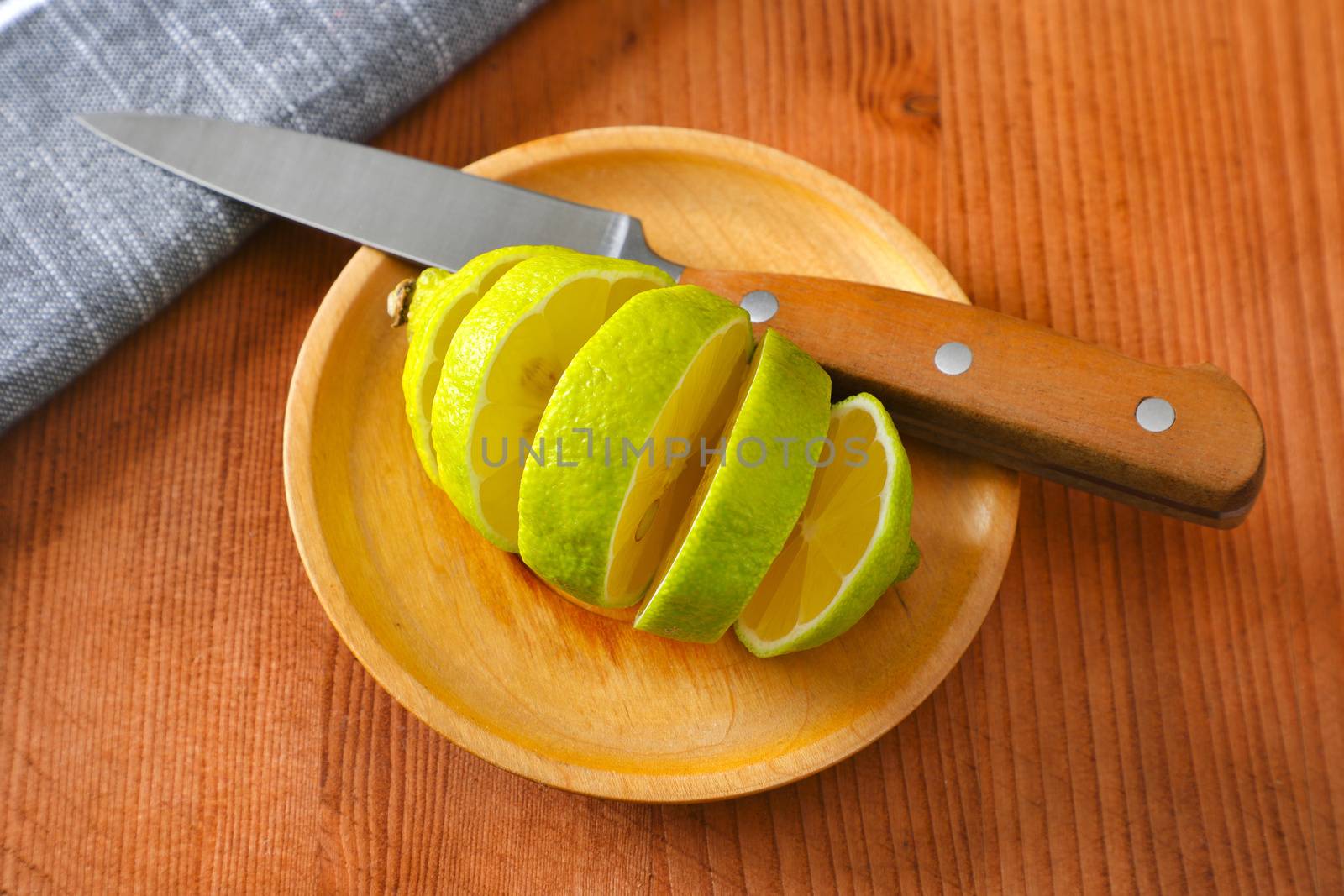 Lemon with green peel and yellow flesh, sliced on wooden plate