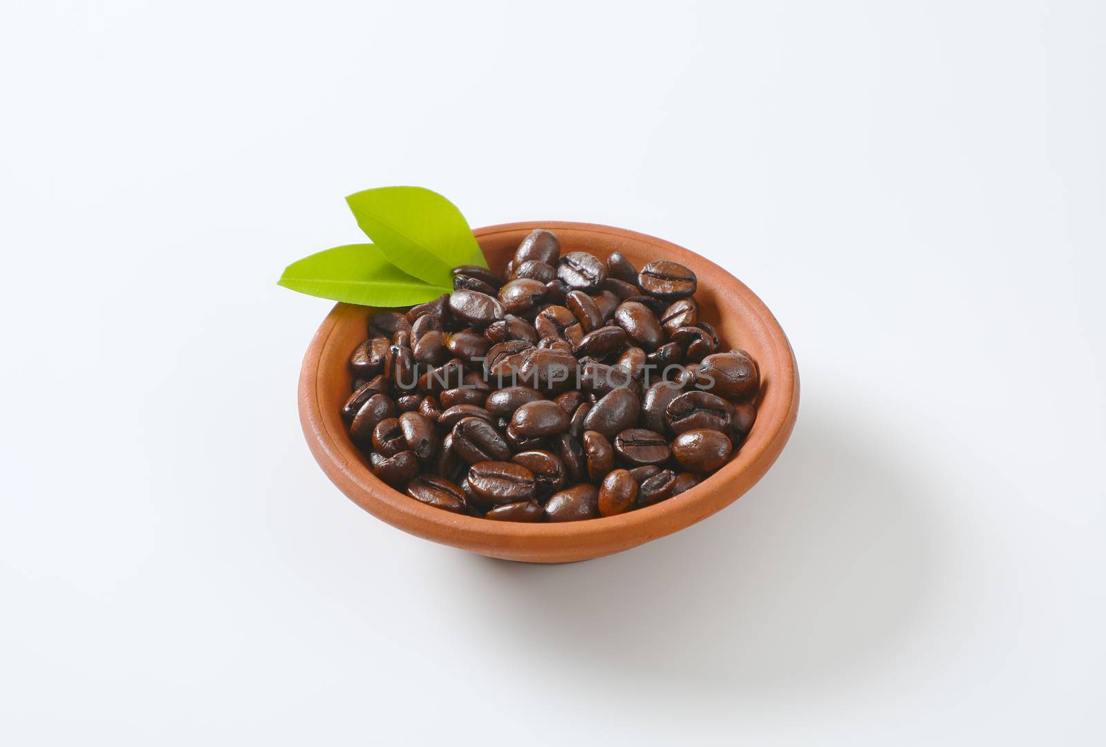 Roasted coffee beans in terracotta bowl