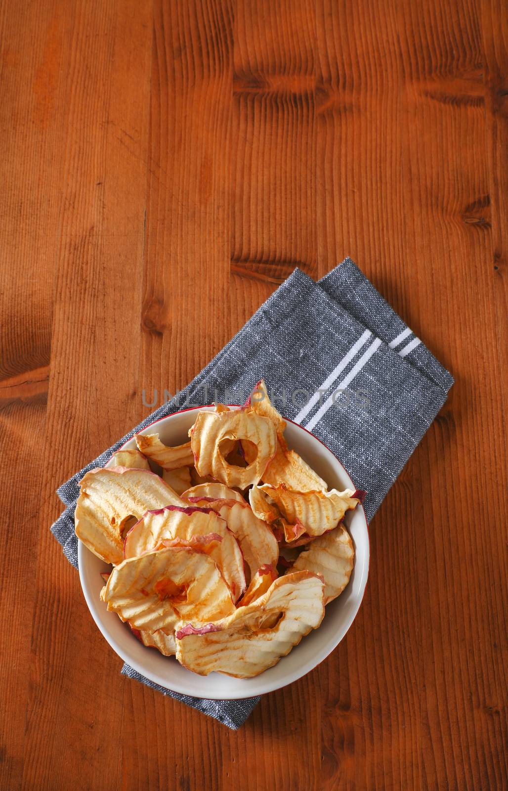 Bowl of dried apple slices - apple chips or rings - on gray napkin