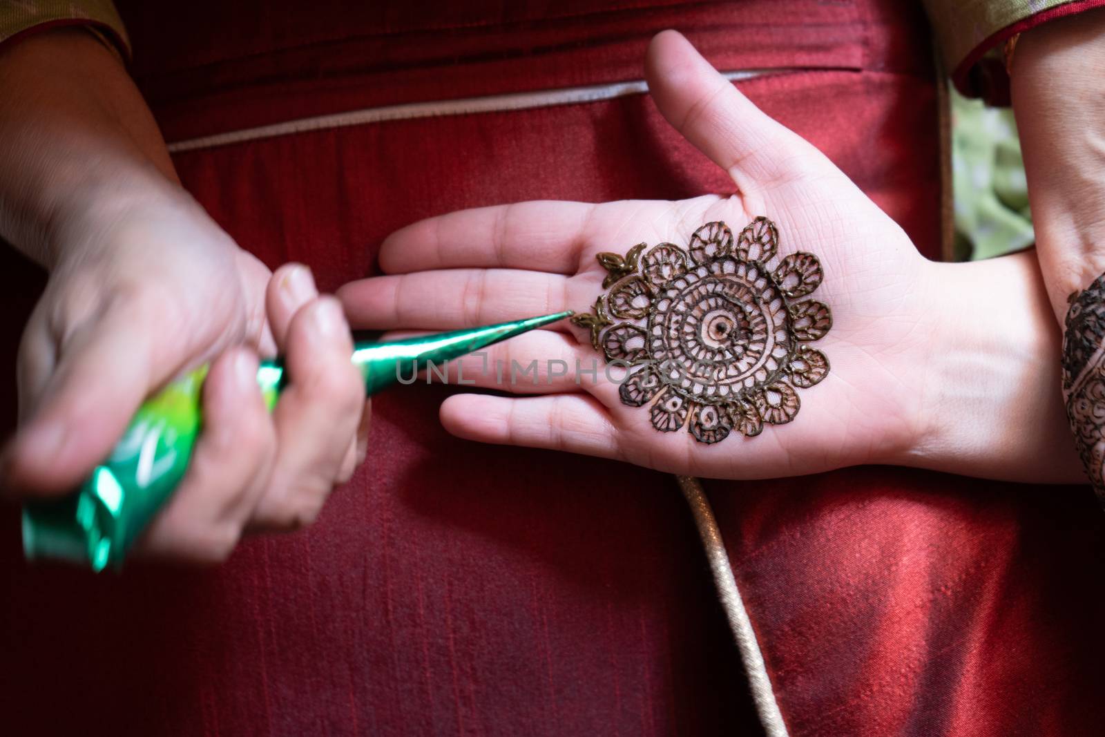 Top down video of a woman copying the mehndi henna tattoo from one hand to the other in preparation of the hindu festival of teej, karwachauth, diwali dussera or a marriage function by Shalinimathur