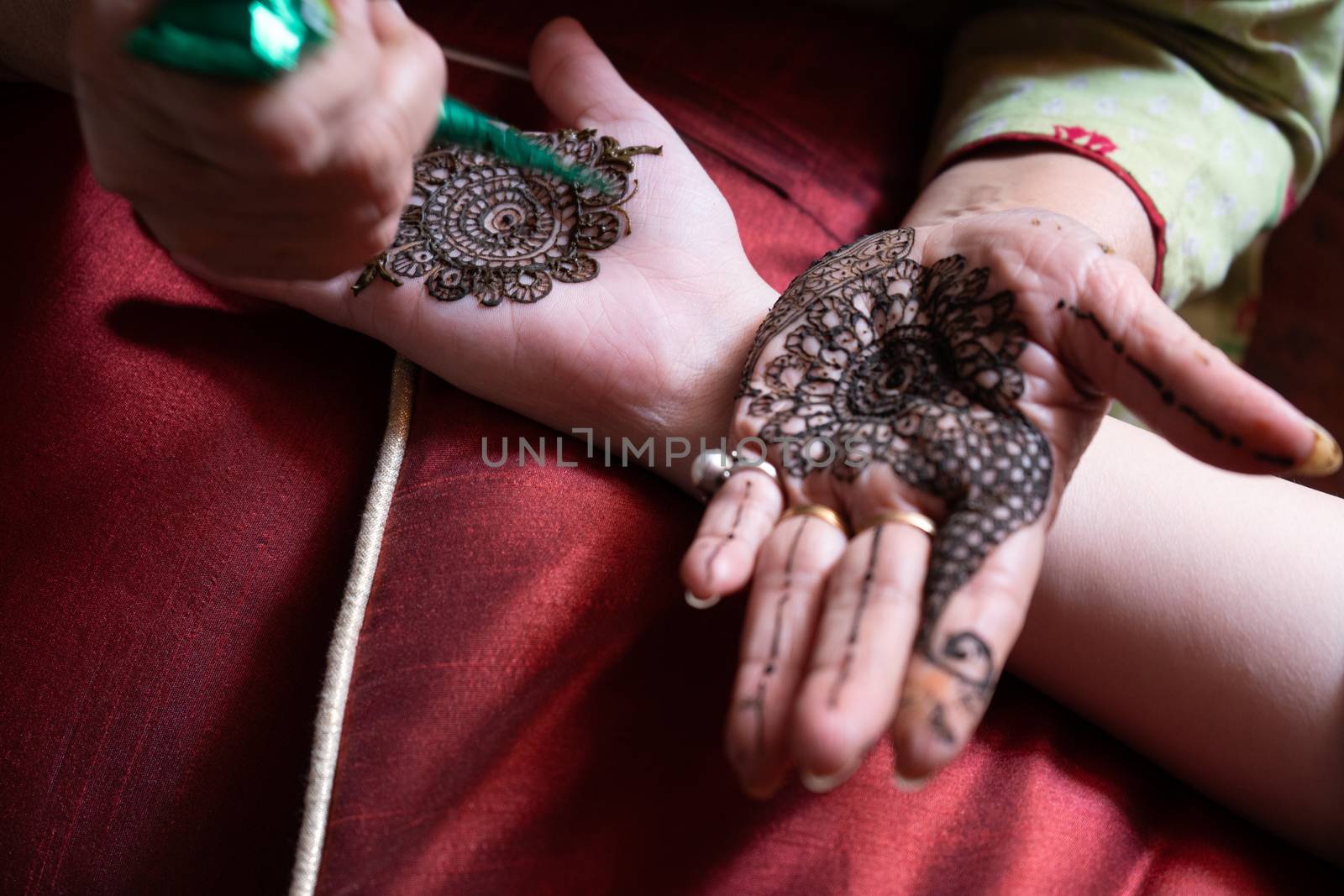 Top down video of a woman copying the mehndi henna tattoo from one hand to the other in preparation of the hindu festival of teej, karwachauth, diwali dussera or a marriage function by Shalinimathur