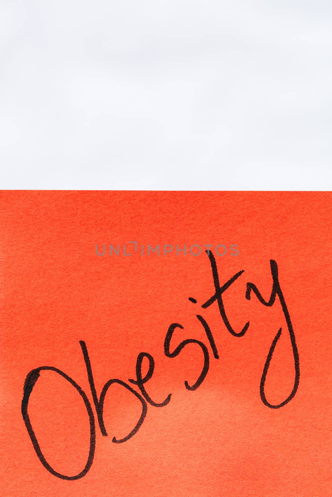 Obesity handwriting text close up isolated on orange paper with  by vladispas