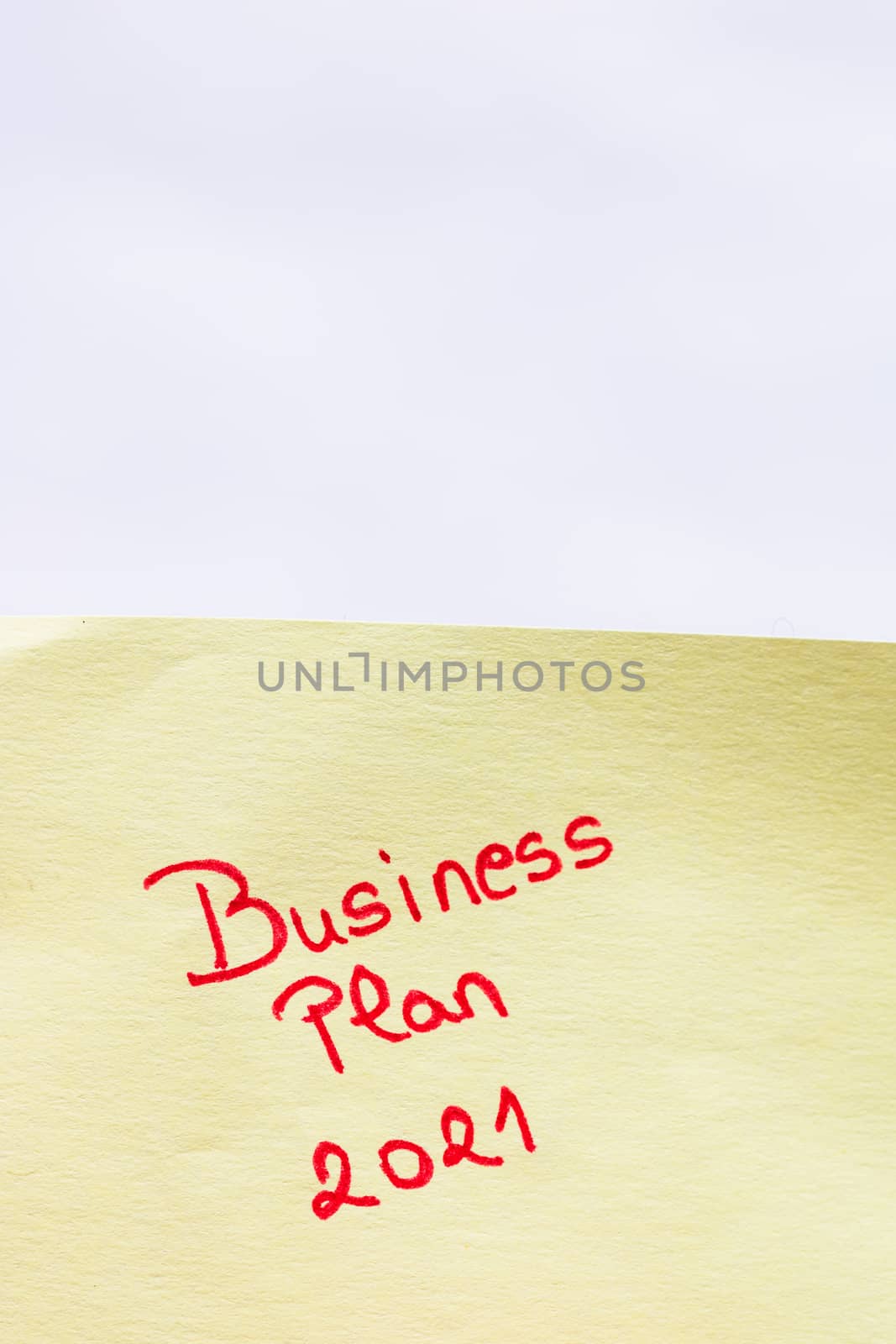 Business plan 2021 handwriting text close up isolated on yellow paper with copy space.
