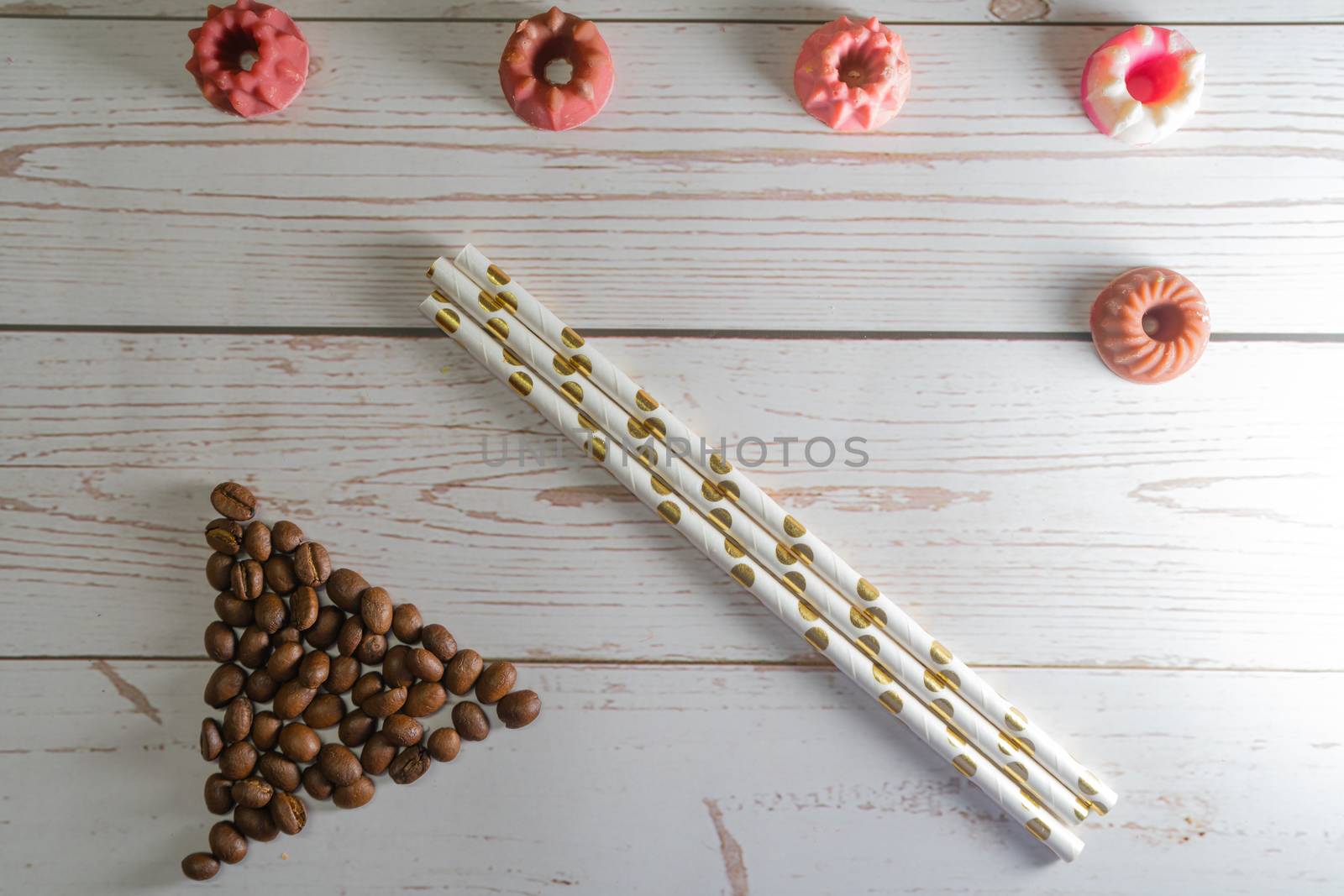 flatlay concept abstract showing coffee beans, straws, candies candles on a white wooden background perfect for a cafe menu or restaurant with copyspace by Shalinimathur