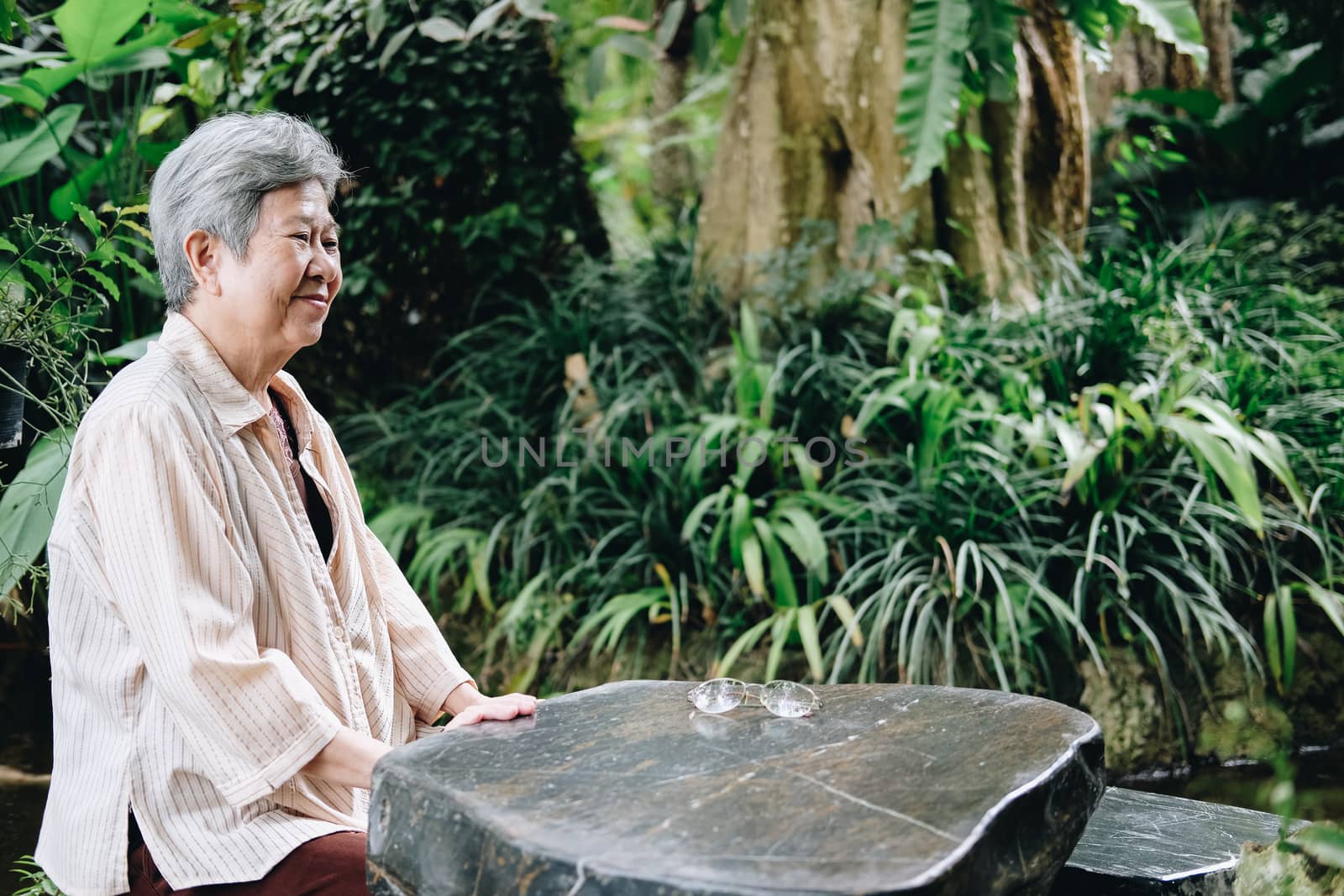 elder woman resting in garden. asian elderly female relaxing outdoors. senior leisure lifestyle