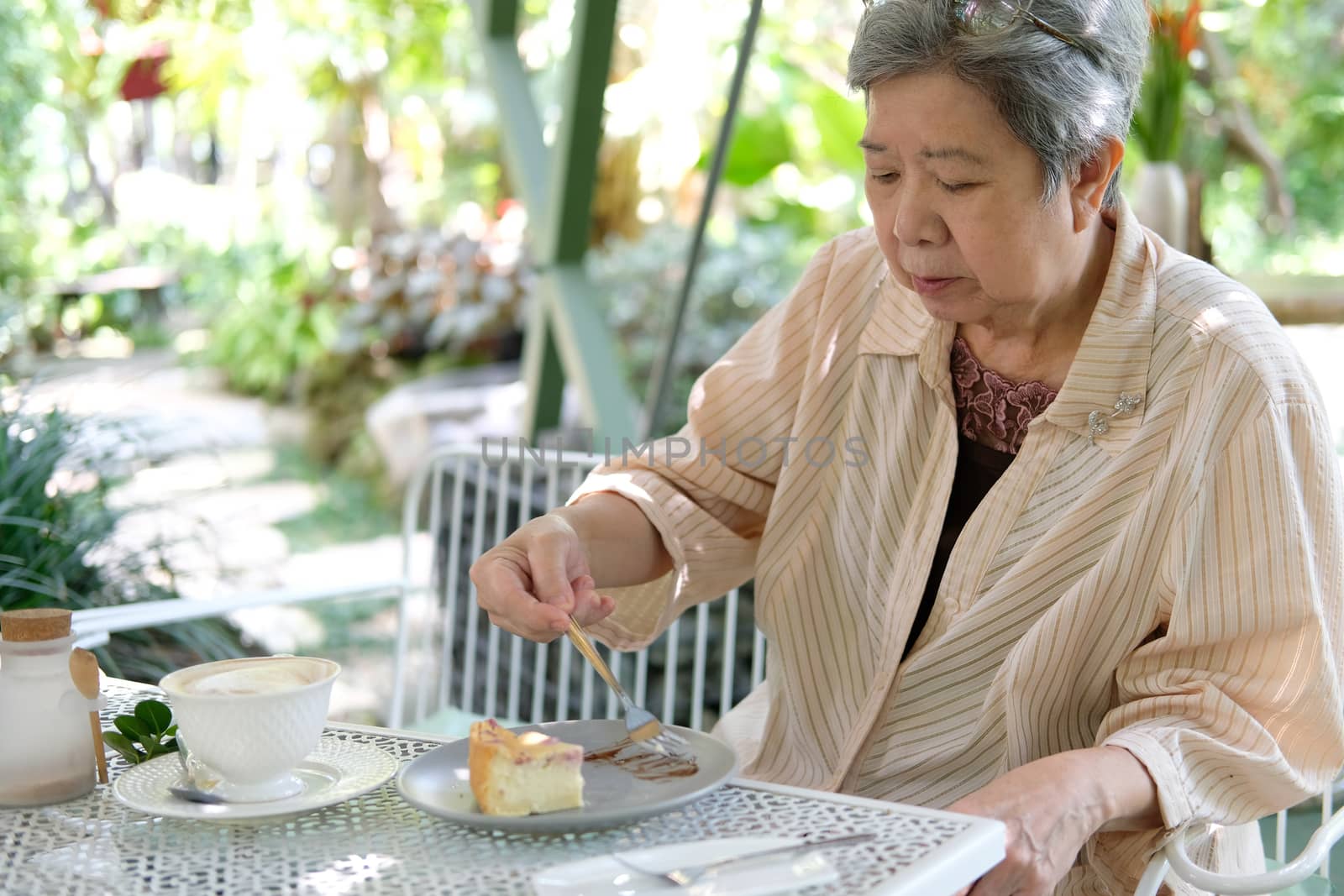 old asian elderly senior elder woman eating cheesecake at restaurant. mature retirement lifestyle