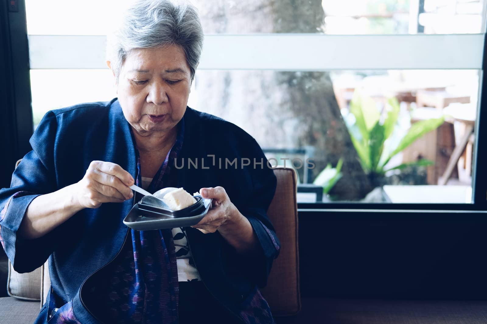 old asian elderly senior elder woman eating cheesecake at restaurant. mature retirement lifestyle