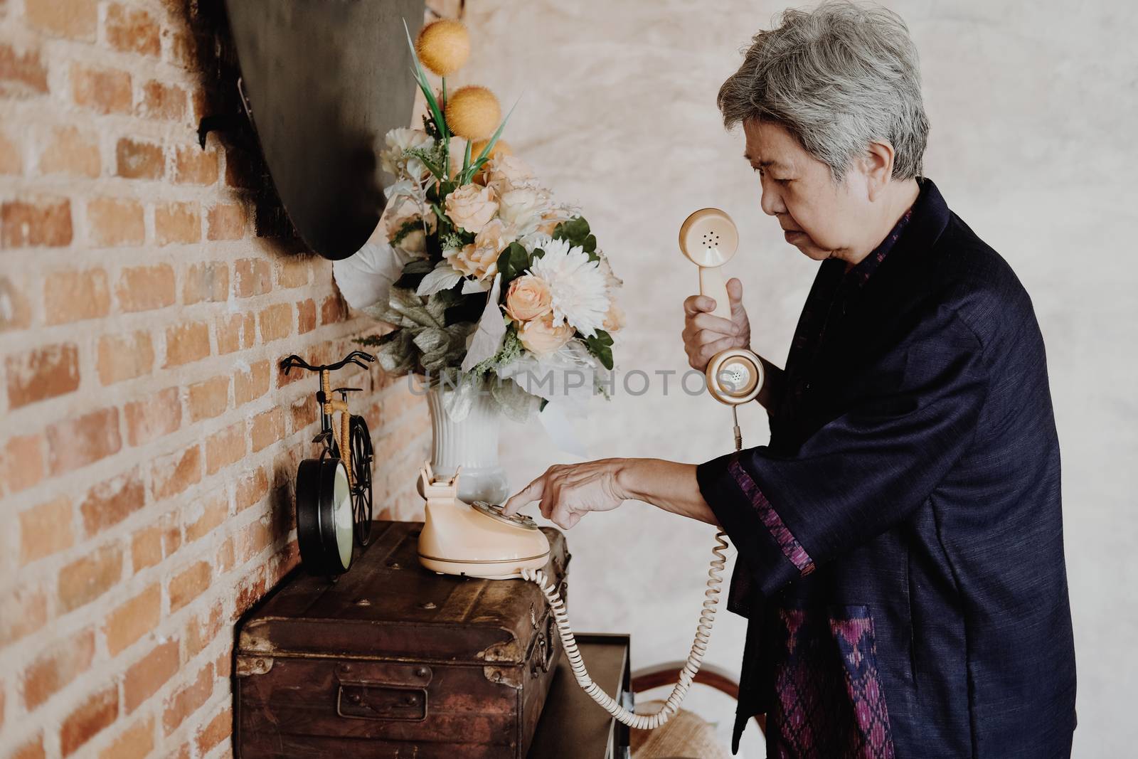 old asian elderly senior elder woman dialing telephone number at home