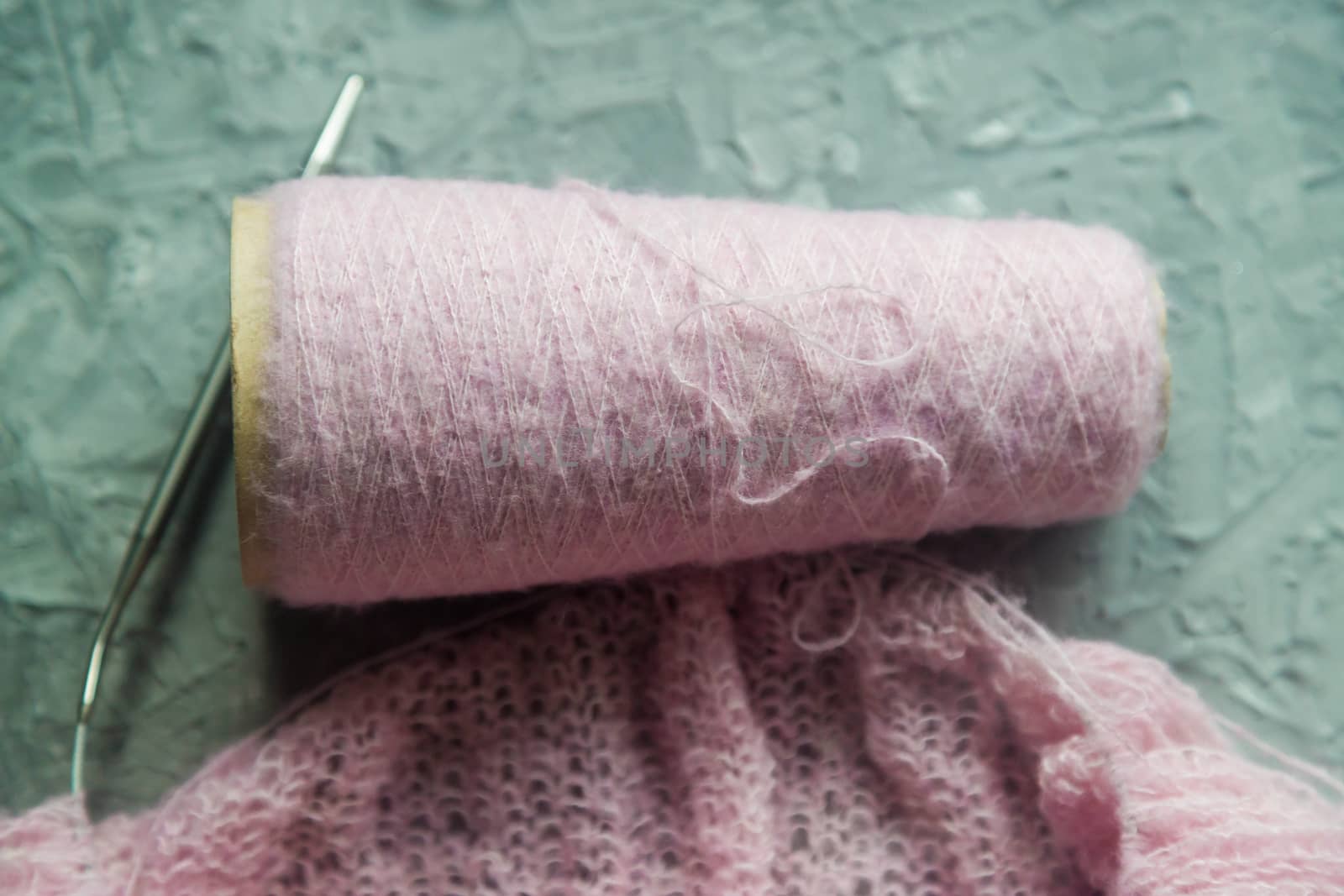 Knitting background flatlay. Bobbin of pink yarn, knitting needles, a knitted pullover on a concrete background, top view. Background about needlework and handicrafts, copy space