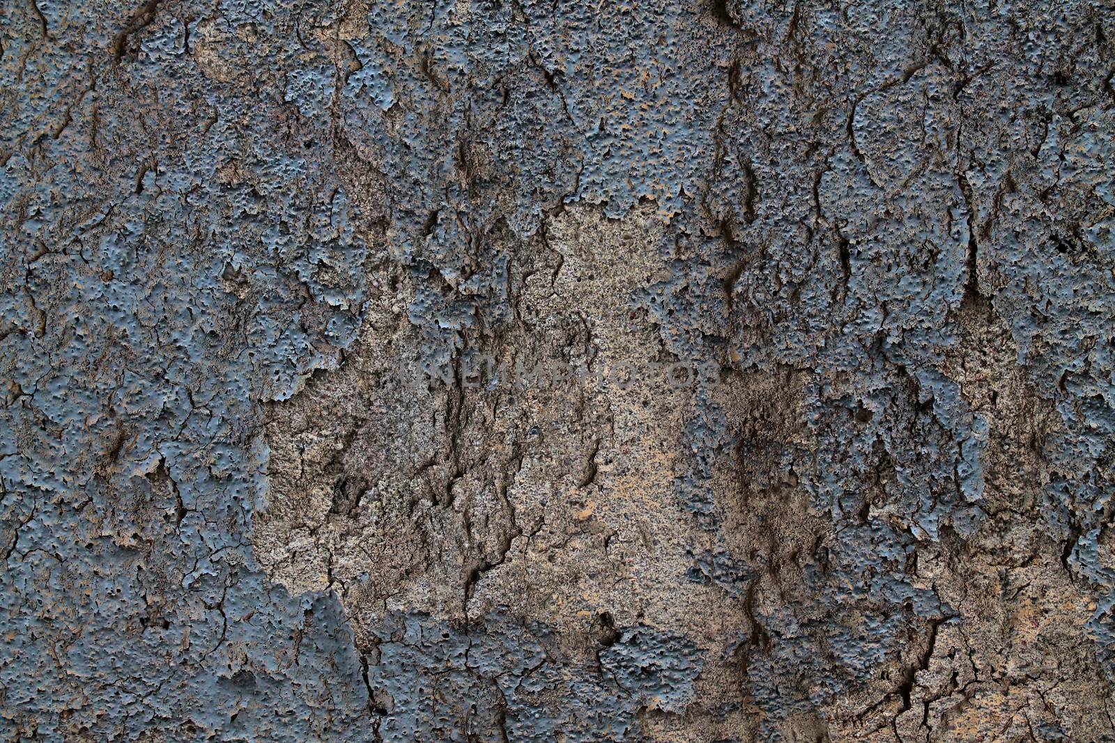 Detailed and colorful close up at cracked and peeling paint on concrete wall textures in high resolution.