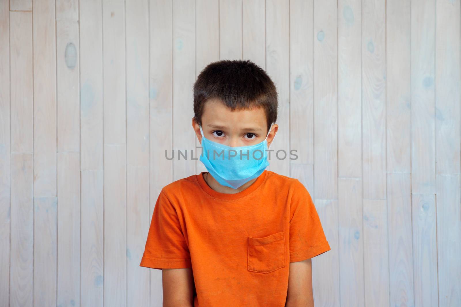 Red zone regions. Little boy in a medical mask looking at the camera. Sad child in a protective mask against coronavirus Covid-19 pneumonia indoors. Patient, quarantine concept. by synel