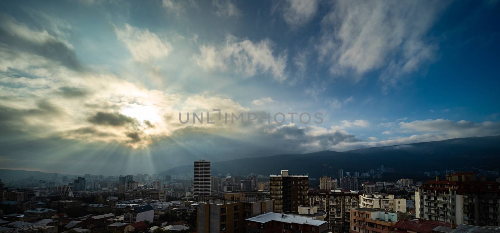 Wide angle view to the modern Tbilisi city centre in the autumnal morning with sunrays through the clous