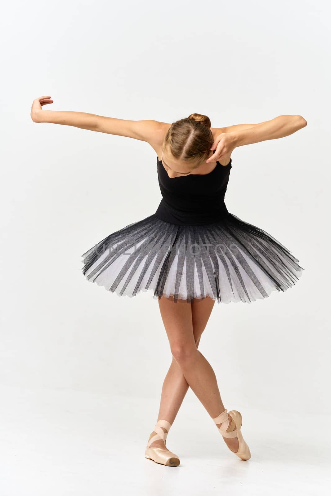 Ballerina in pointe shoes and tutu dancing on isolated background leaning forward