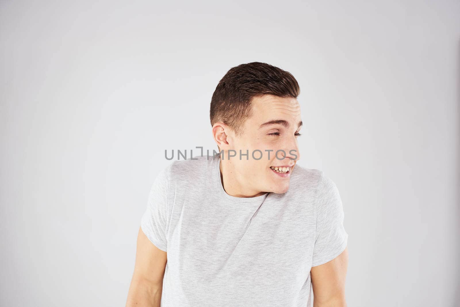 Man in a white t-shirt emotions gestures with hands close-up cropped view light background. High quality photo