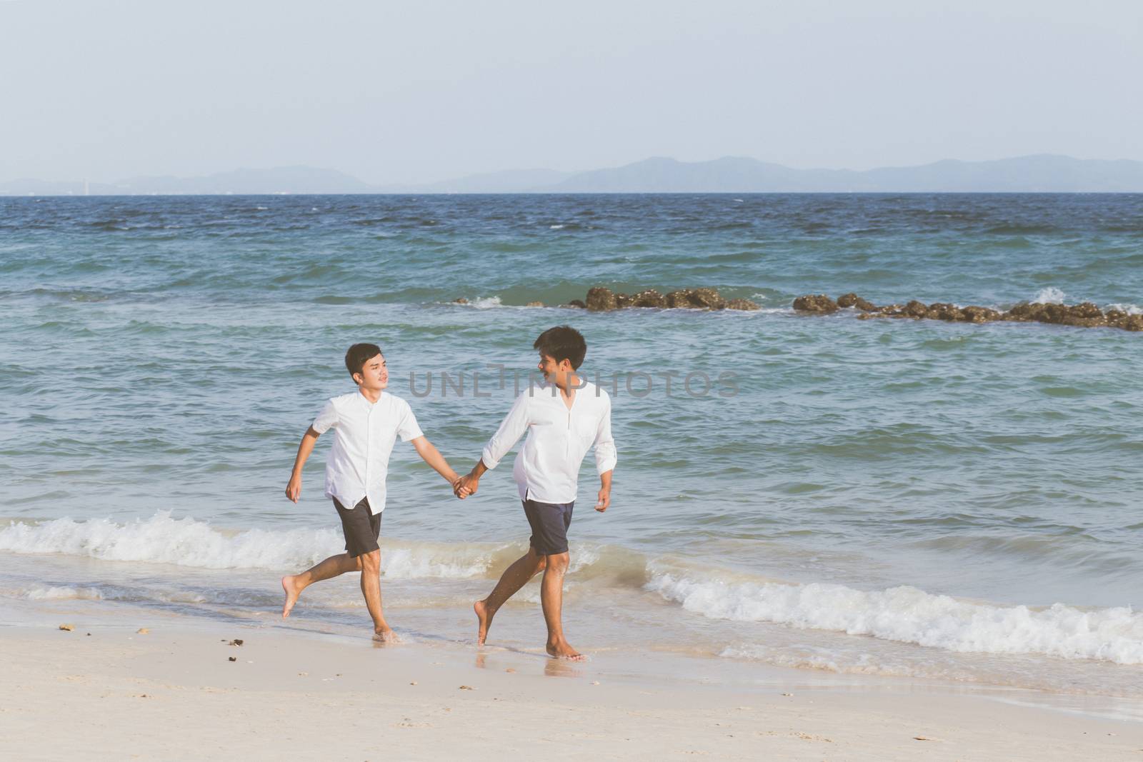 Homosexual portrait young asian couple running with cheerful together on beach in summer, asia gay going tourism for leisure and relax with happiness in vacation at sea, LGBT legal concept.