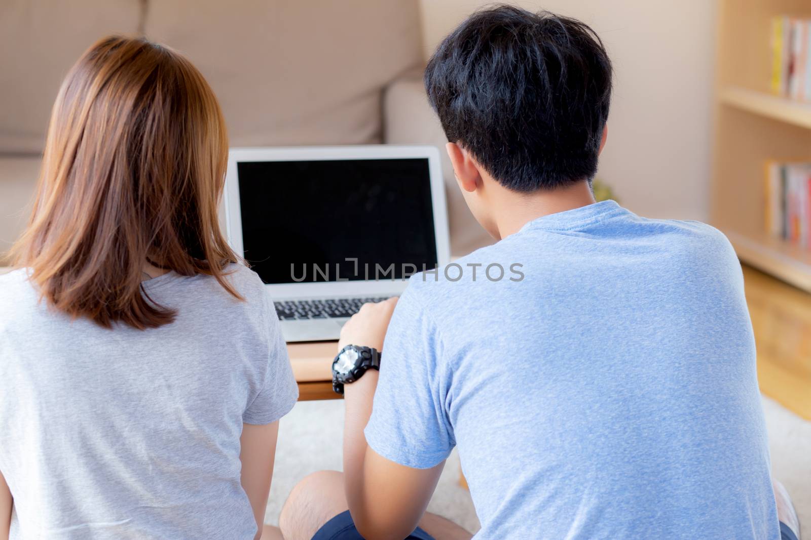 Back view of young asian couple working laptop with blank screen by nnudoo