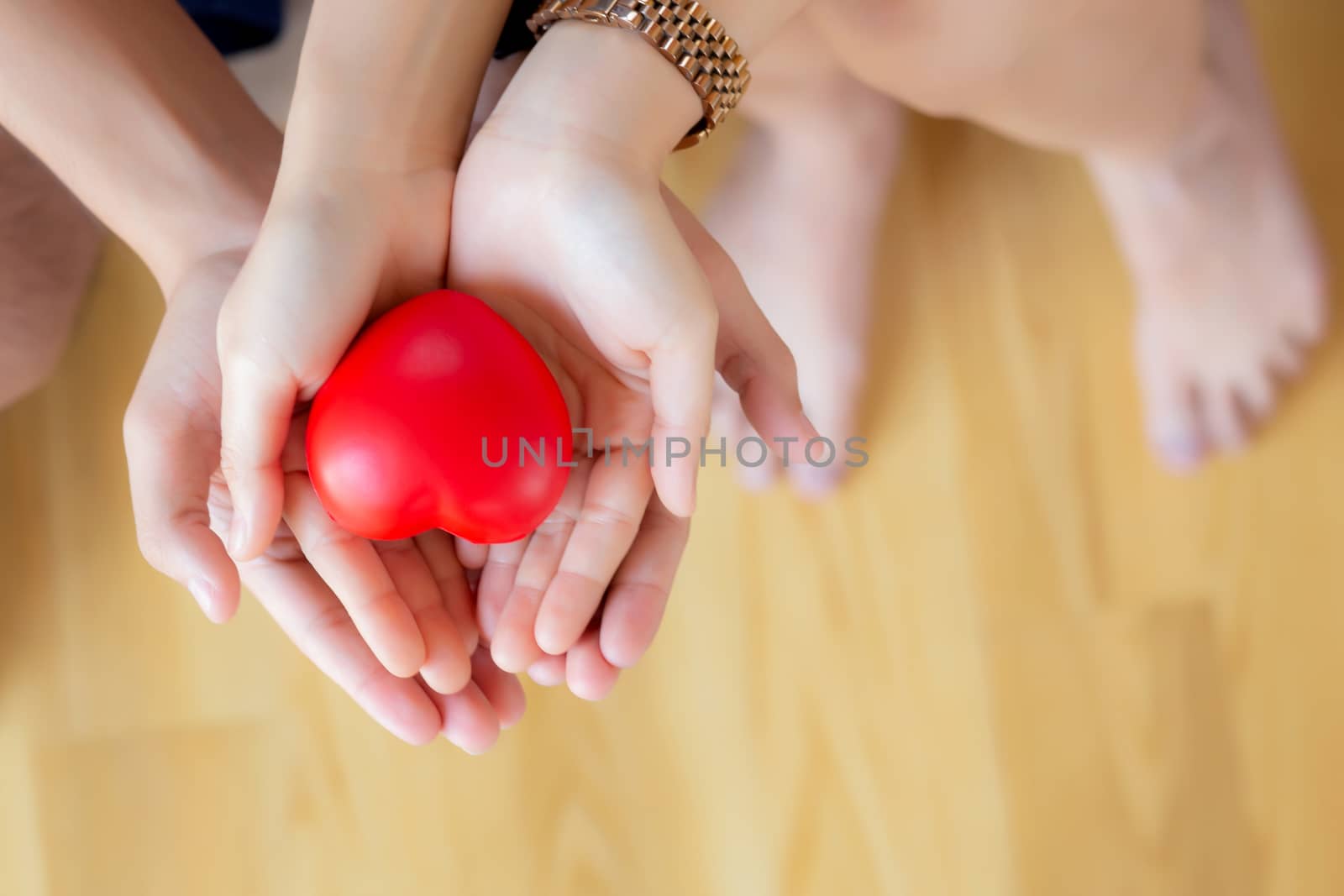Closeup asian couple holding a red heart shape on hands, hands of man and woman feeling happiness and romantic take care together, family and partnership in holiday and valentine concept.