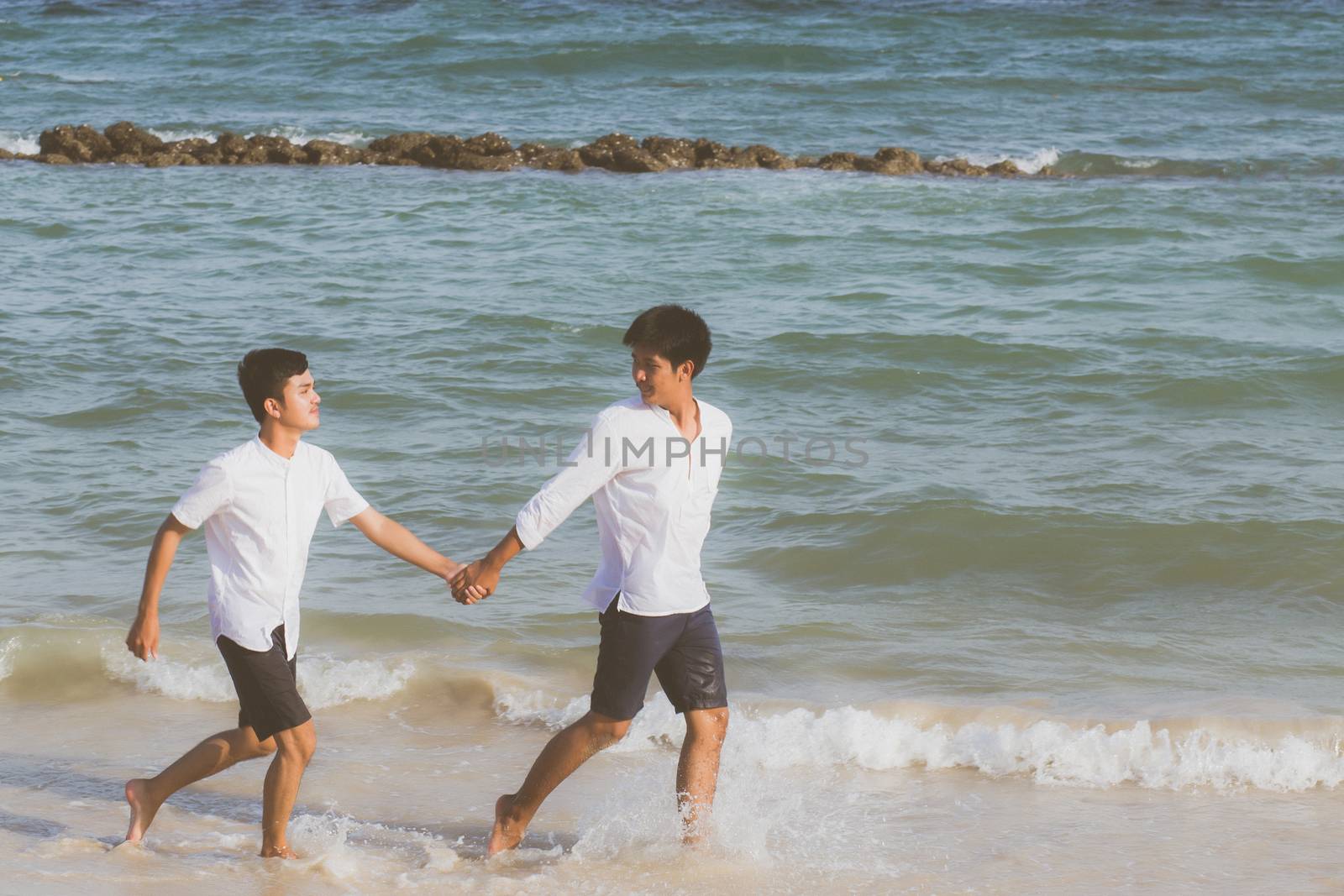 Homosexual portrait young asian couple running with cheerful together on beach in summer, asia gay going tourism for leisure and relax with happiness in vacation at sea, LGBT legal concept.