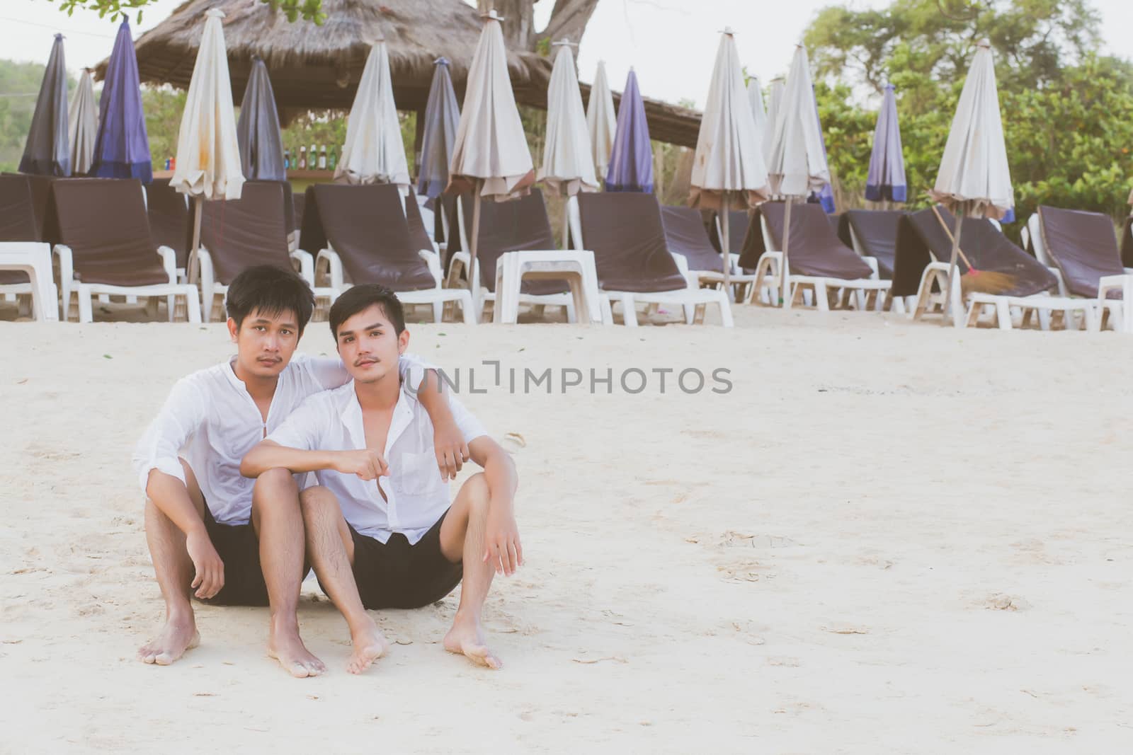 Homosexual portrait young asian couple sitting hug together on beach in summer, asia gay going tourism for leisure and relax with romantic and happiness in vacation at sea, LGBT legal concept.