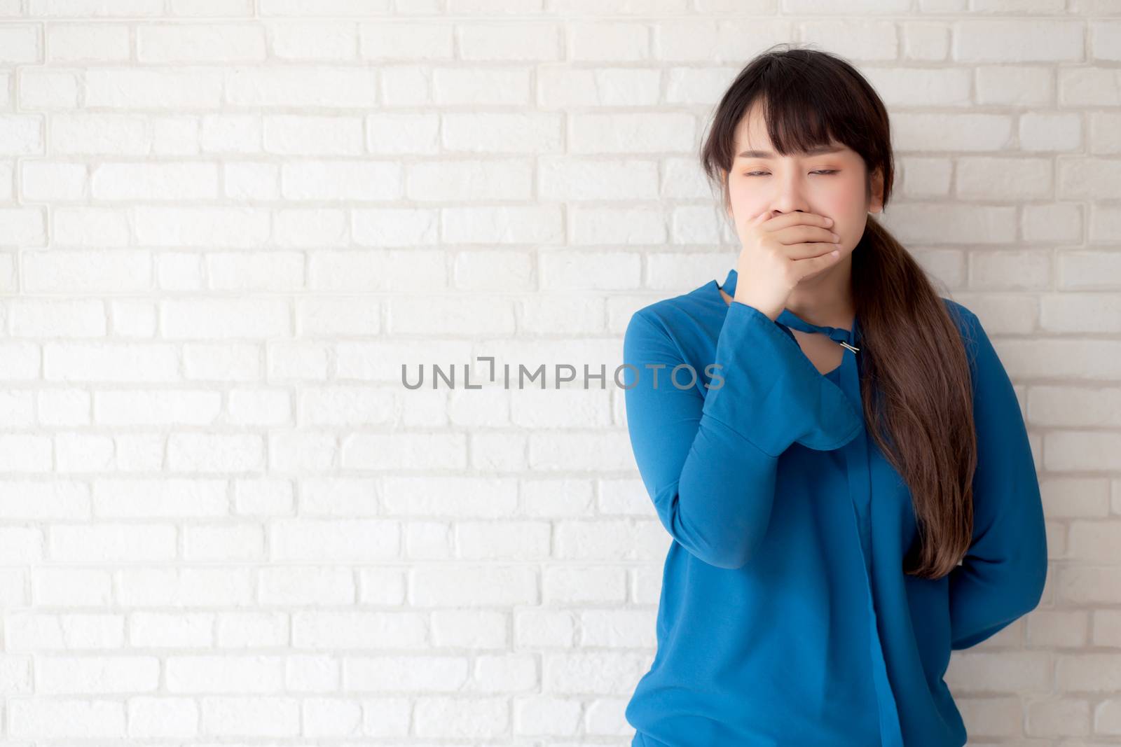 Beautiful portrait young asian woman yawning and sleepy on grey cement texture grunge wall brick background, beauty asia girl expression lazy and bored, female leisure and relax, lifestyle concept.