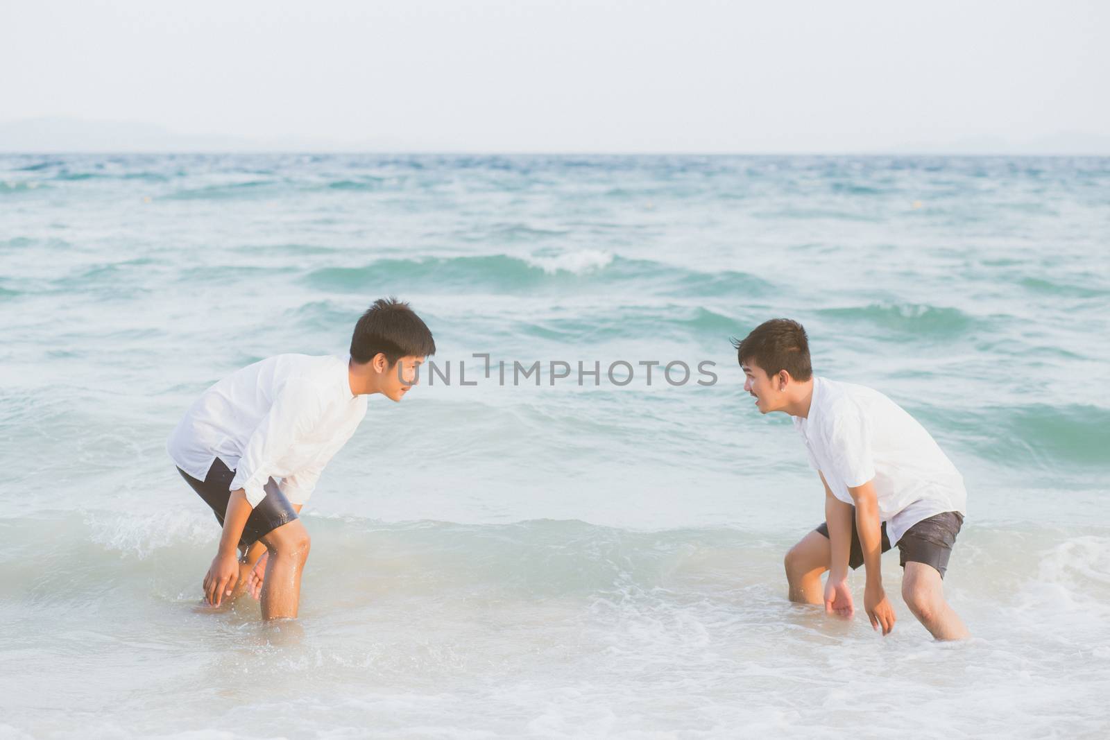 Homosexual portrait young asian couple play water on beach with cheerful together in summer, tourism of asia gay fun for leisure and relax with happiness in vacation at sea, LGBT legal concept.