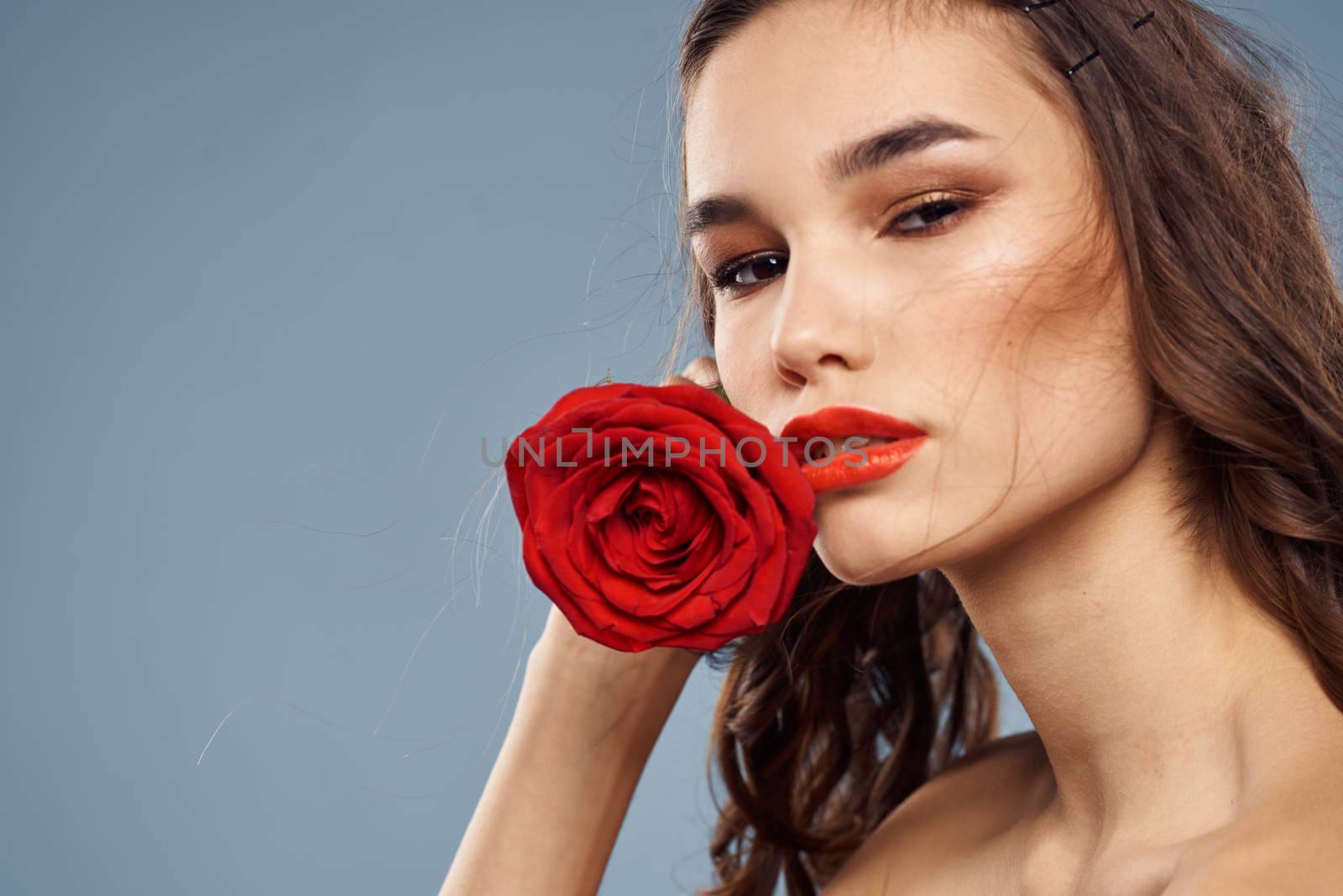 Portrait of a woman with a red rose in her hands on a gray background naked shoulders evening makeup by SHOTPRIME