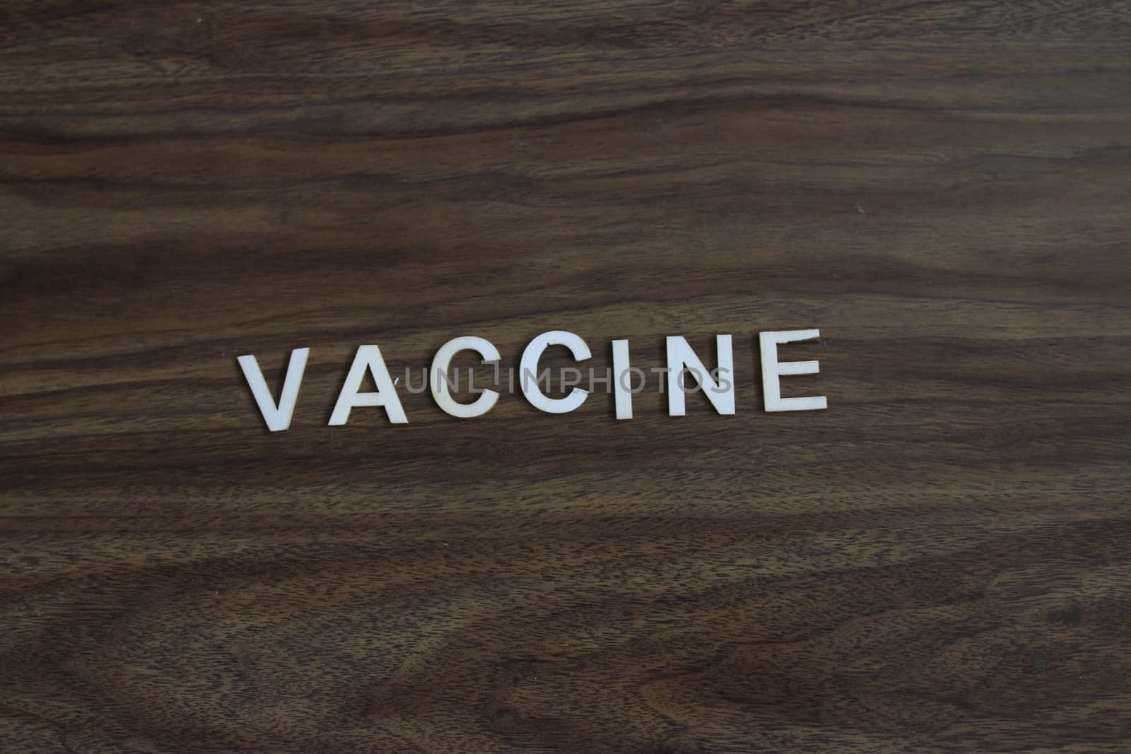the word vaccine on a wood background. room for copyspace. by mynewturtle1
