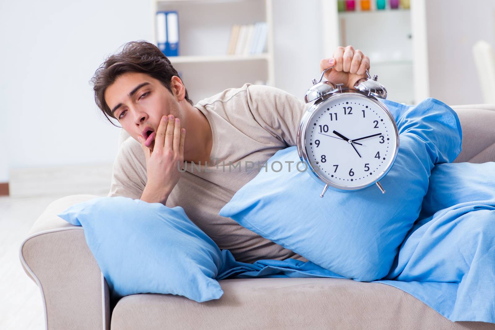 Man having trouble waking up with alarm clock