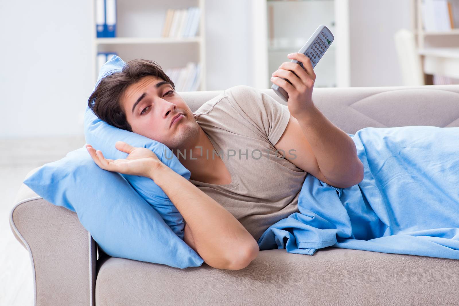 Man watching tv from bed holding remote control unit