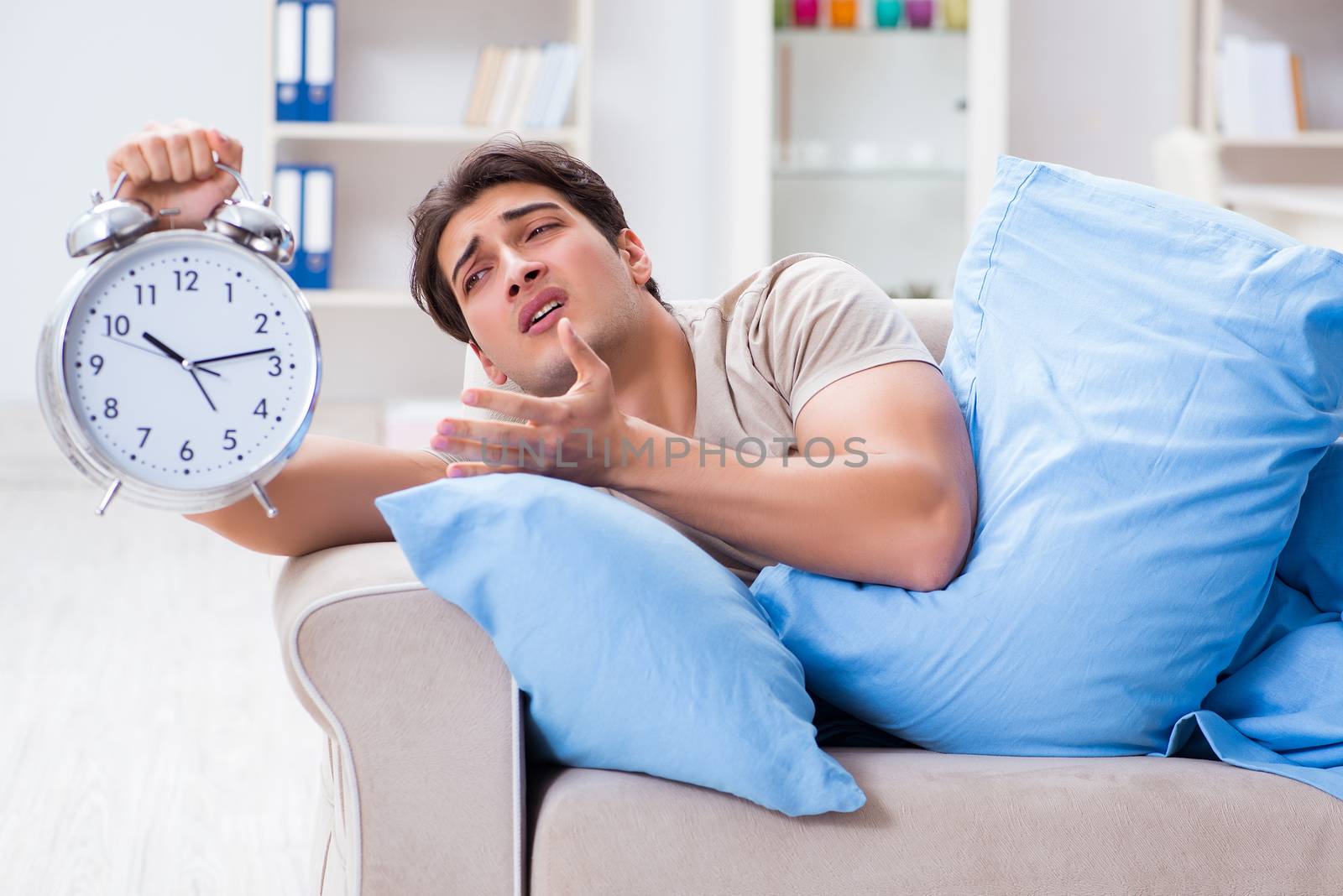 Man having trouble waking up with alarm clock