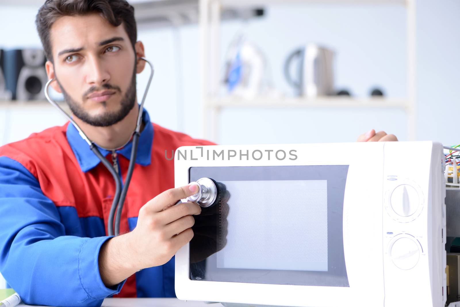Young repairman fixing and repairing microwave oven by Elnur
