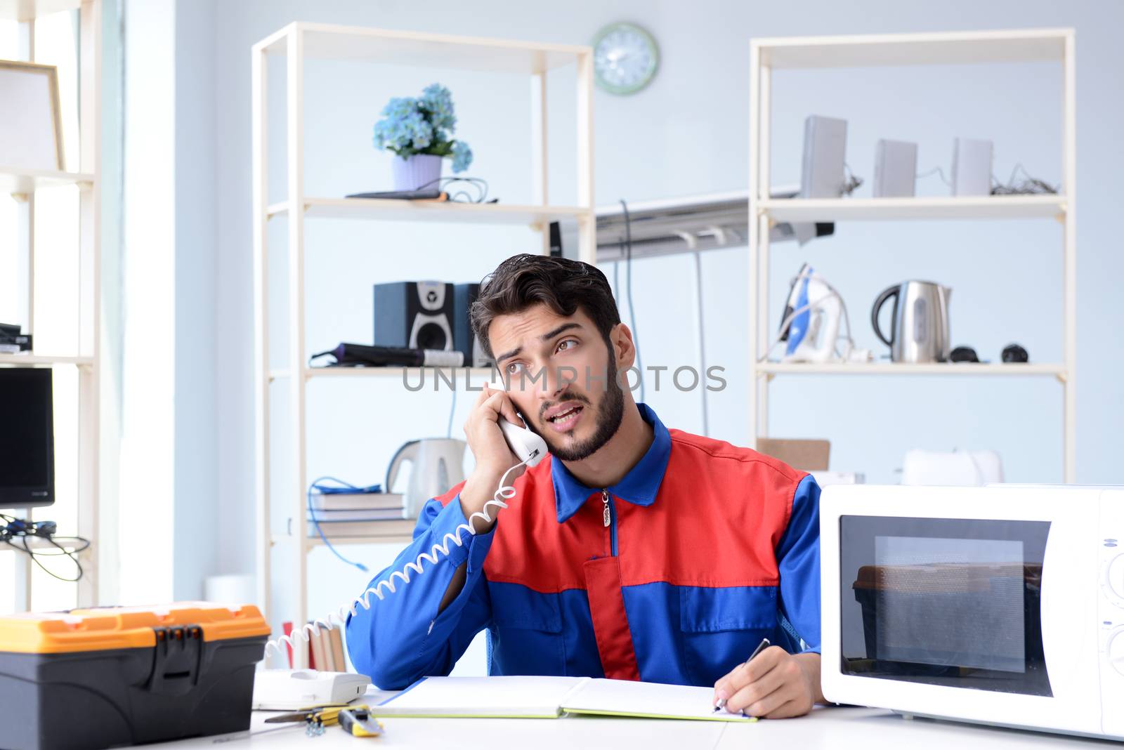 Young repairman fixing and repairing microwave oven