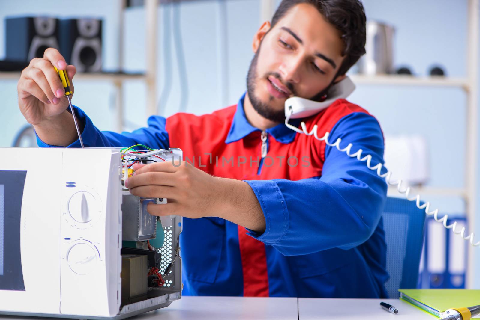 Young repairman fixing and repairing microwave oven