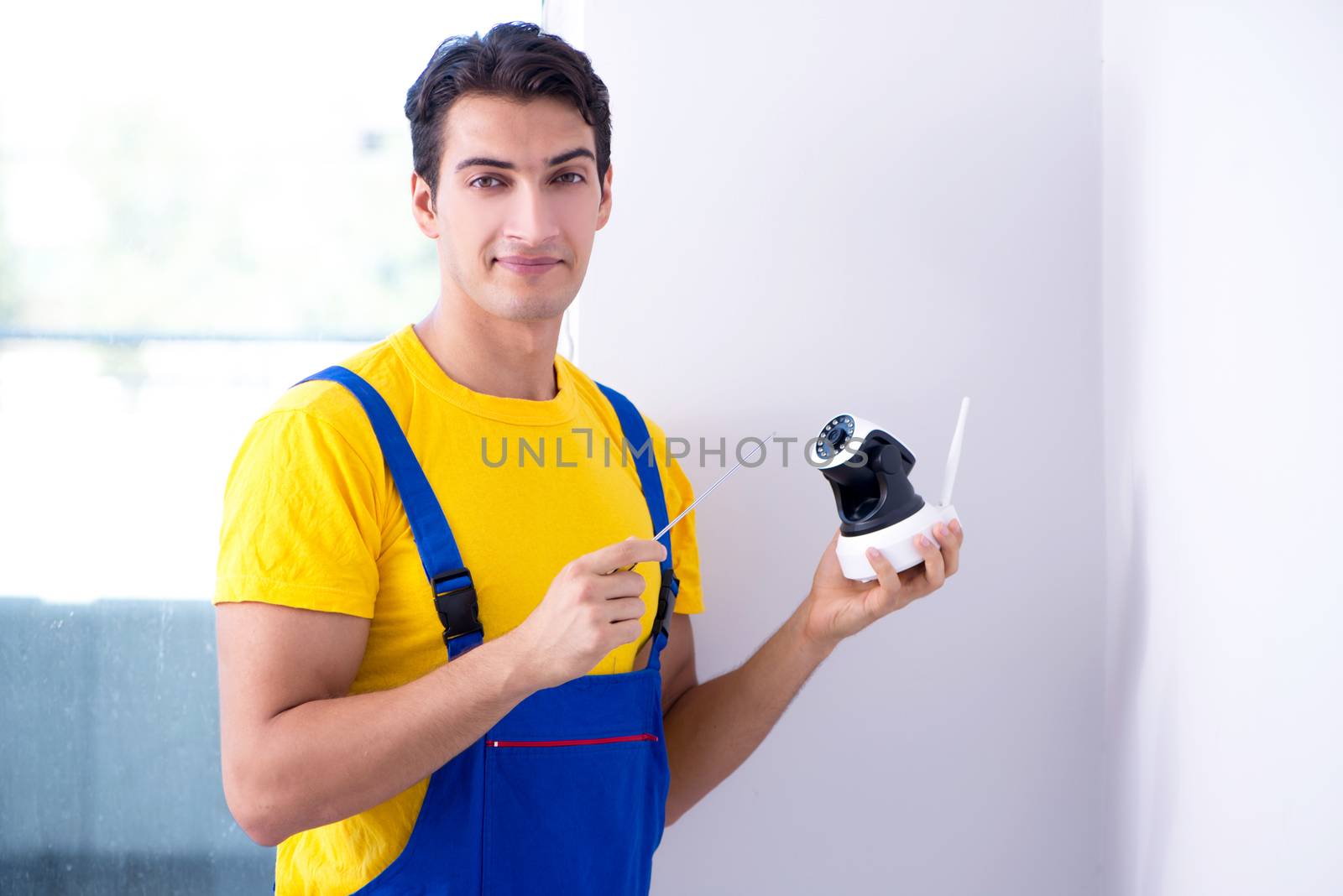 Contractor installing surveillance CCTV cameras in office
