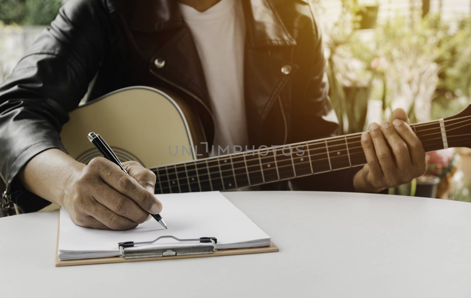 A Song writer holding pen for compose a song. Musician playing acoustic guitar. Live music and abstract musical concept.