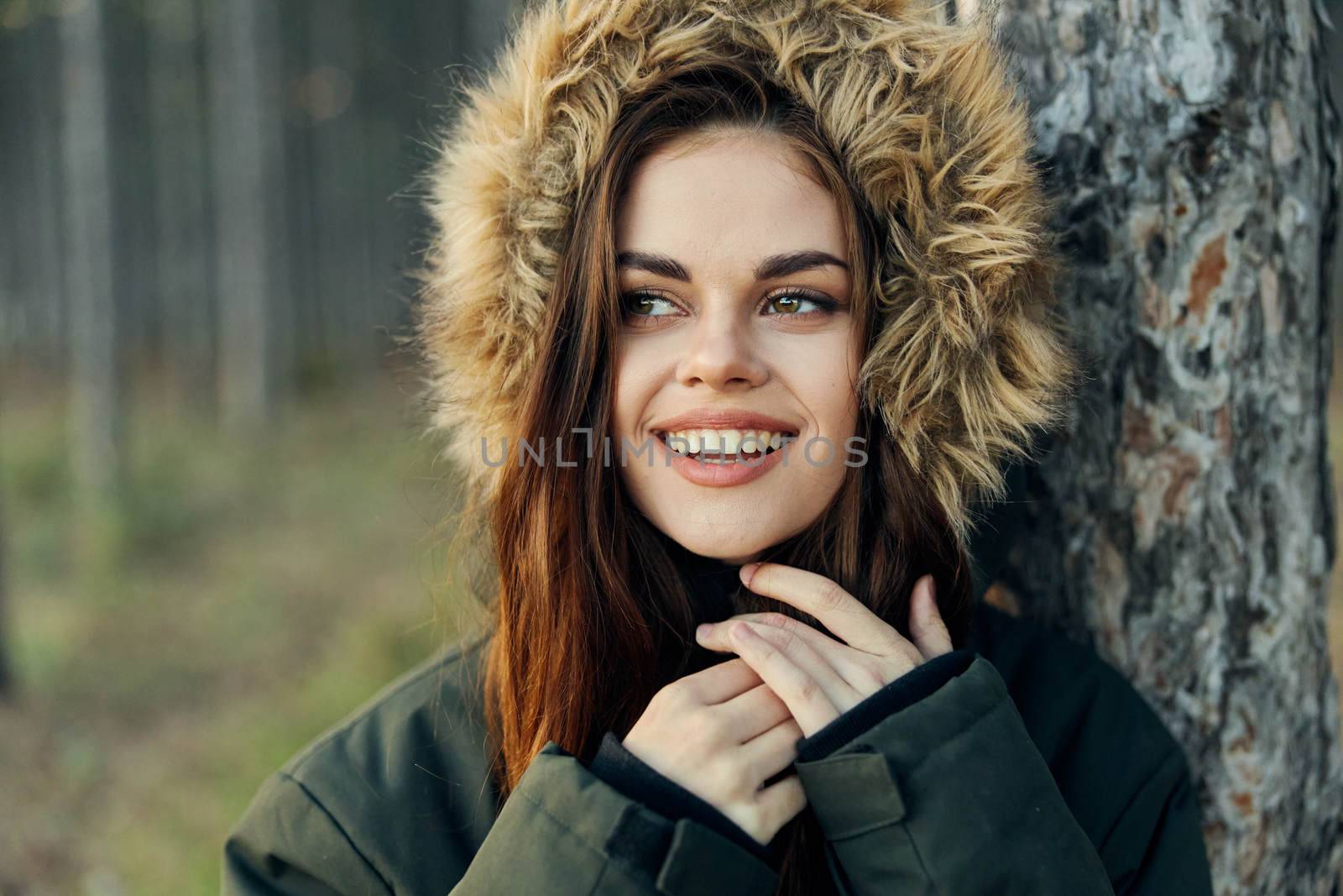 smiling woman with a hood on her head near a tree outdoors close-up. High quality photo