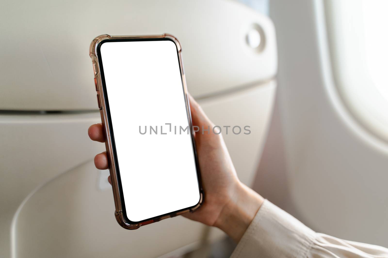 Woman on board of an airplane with white screen mobile mockup in hand.