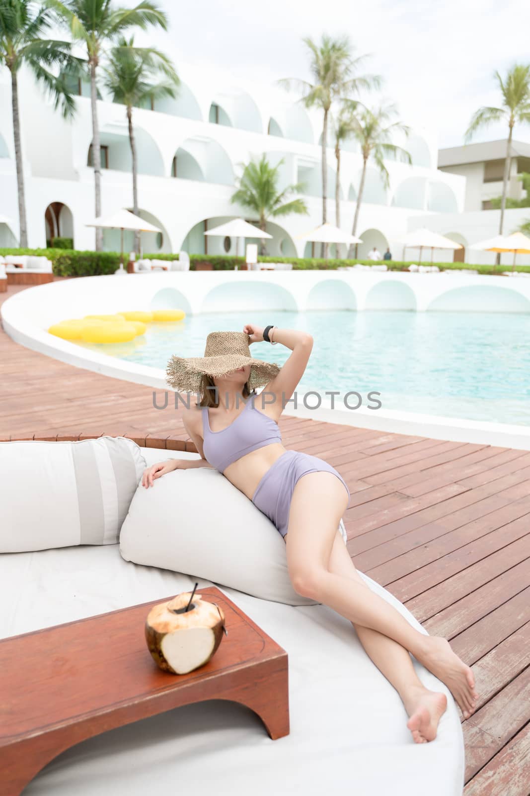 Woman relaxing by the pool with coconuts, summer vacation.