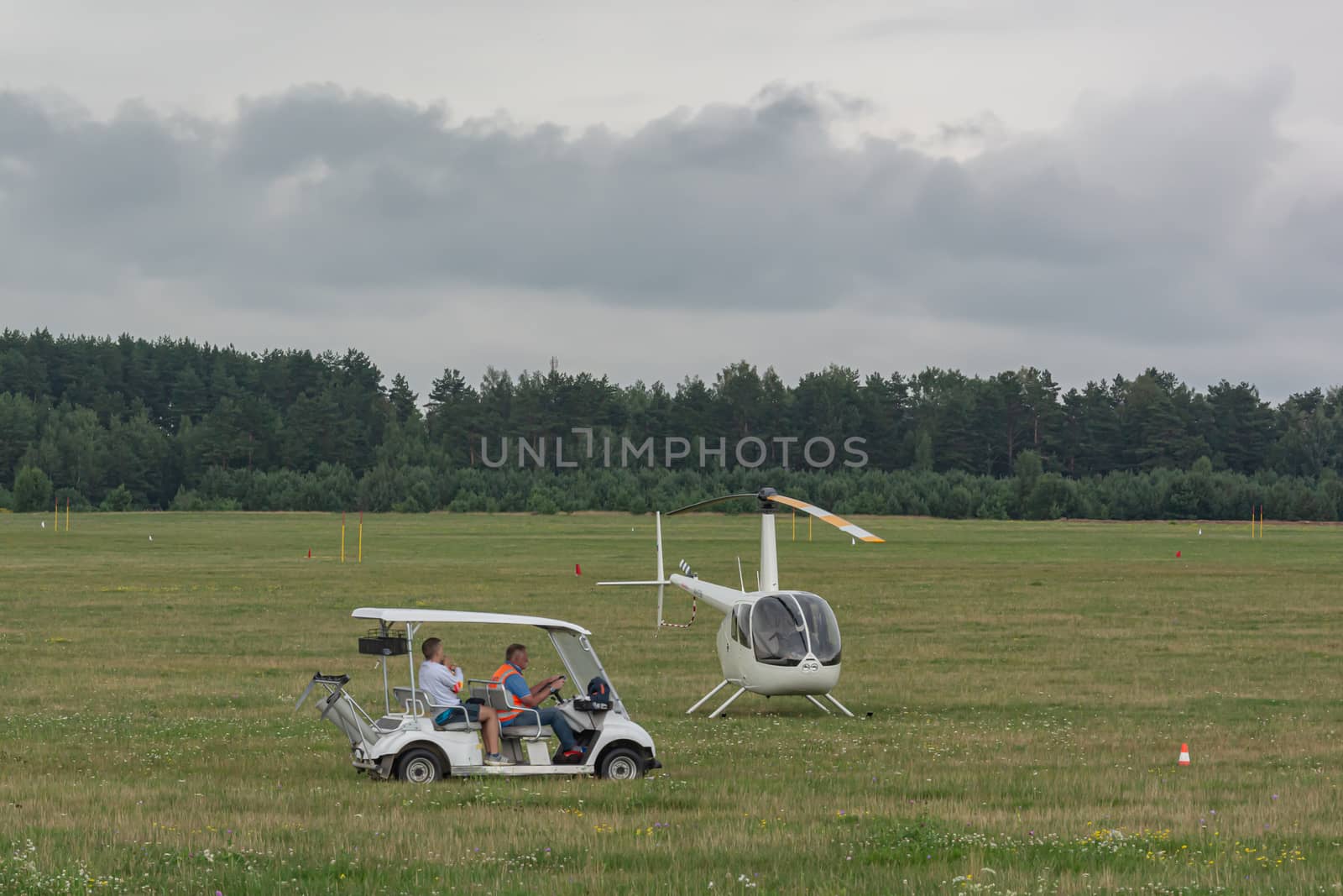 Belarus, Minsk - 07/25/2018: electric car and two-seater helicopter on the green field of the airfield. Stock photography
