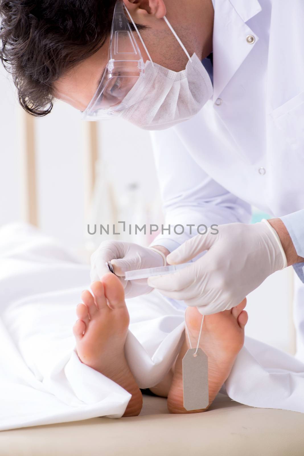 Police coroner examining dead body corpse in morgue